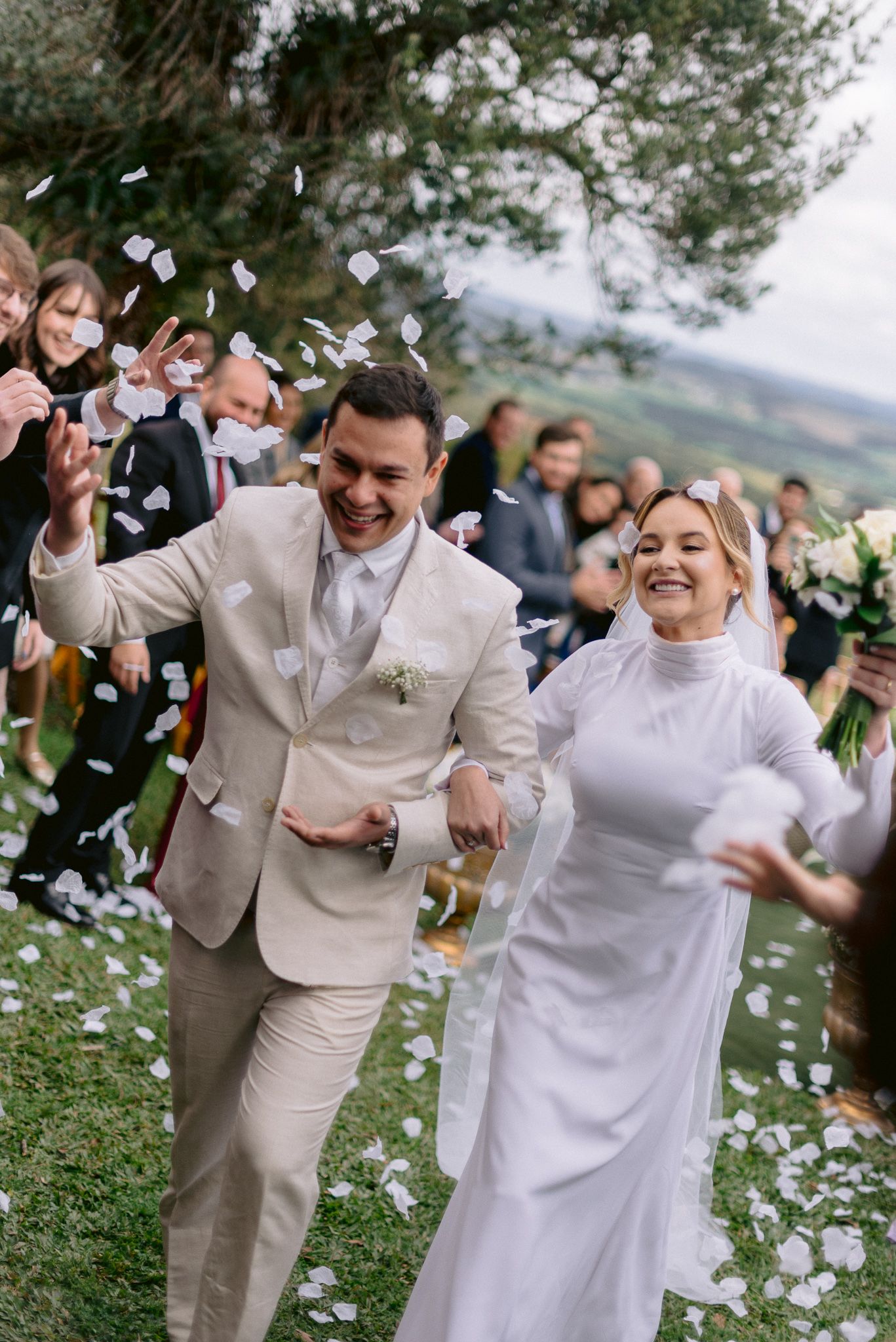 Joyful wedding celebration with flower petals and guests celebrating outdoors.