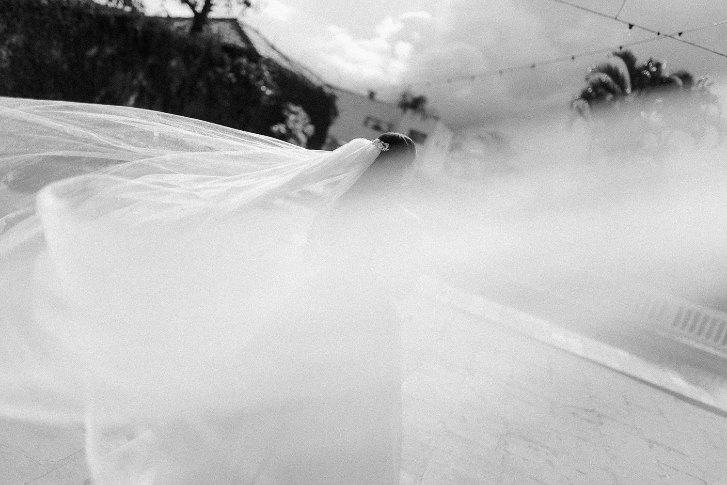Flowing white veil creates dramatic movement in black and white photography sequence.