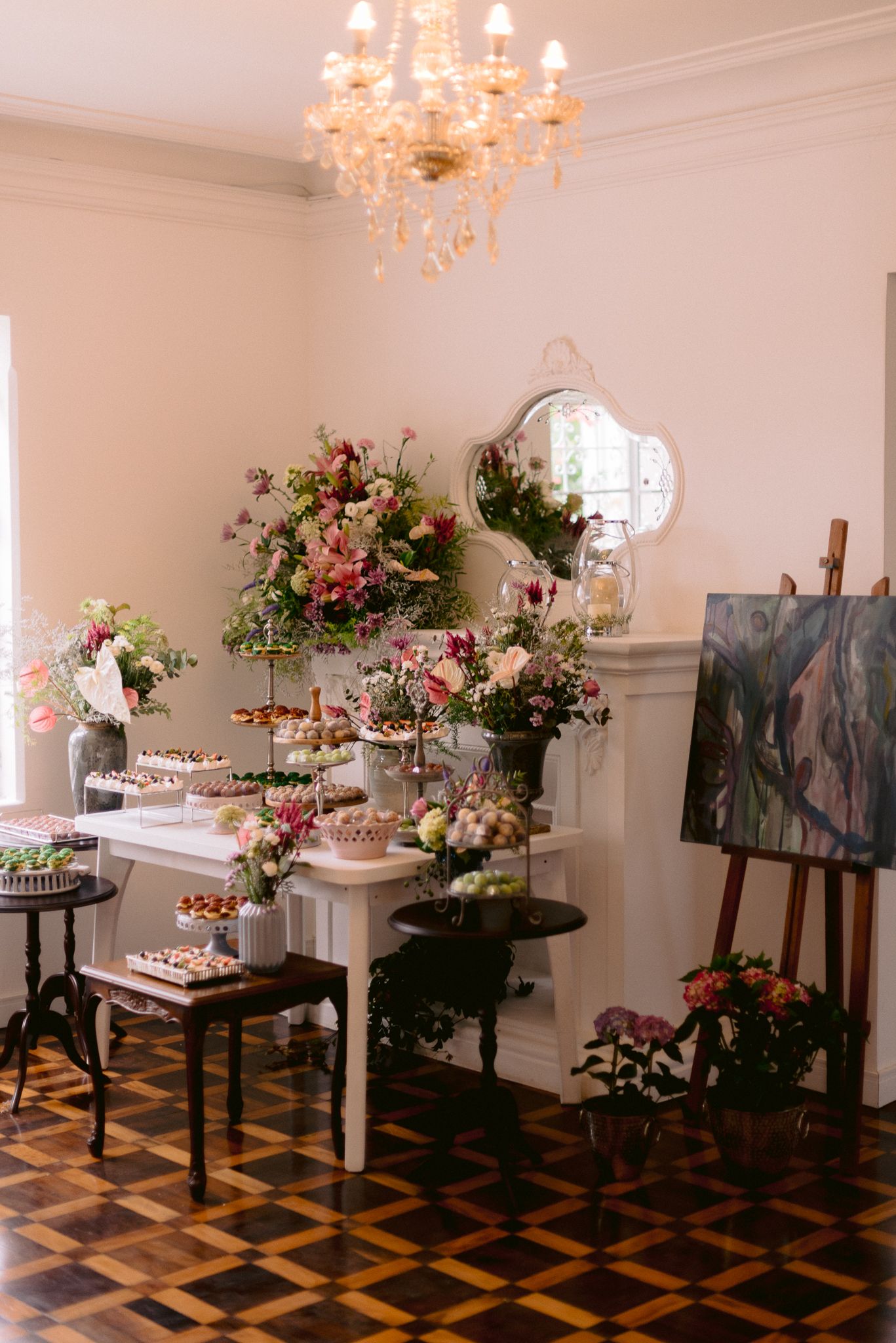 Elegant wedding reception room with chandelier and floral arrangements on display tables.