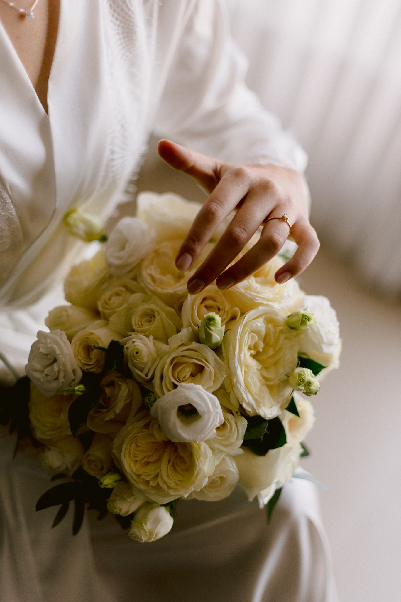 A series of four similar shots showing hands in white delicately holding a beautiful bouquet of cream-colored roses.