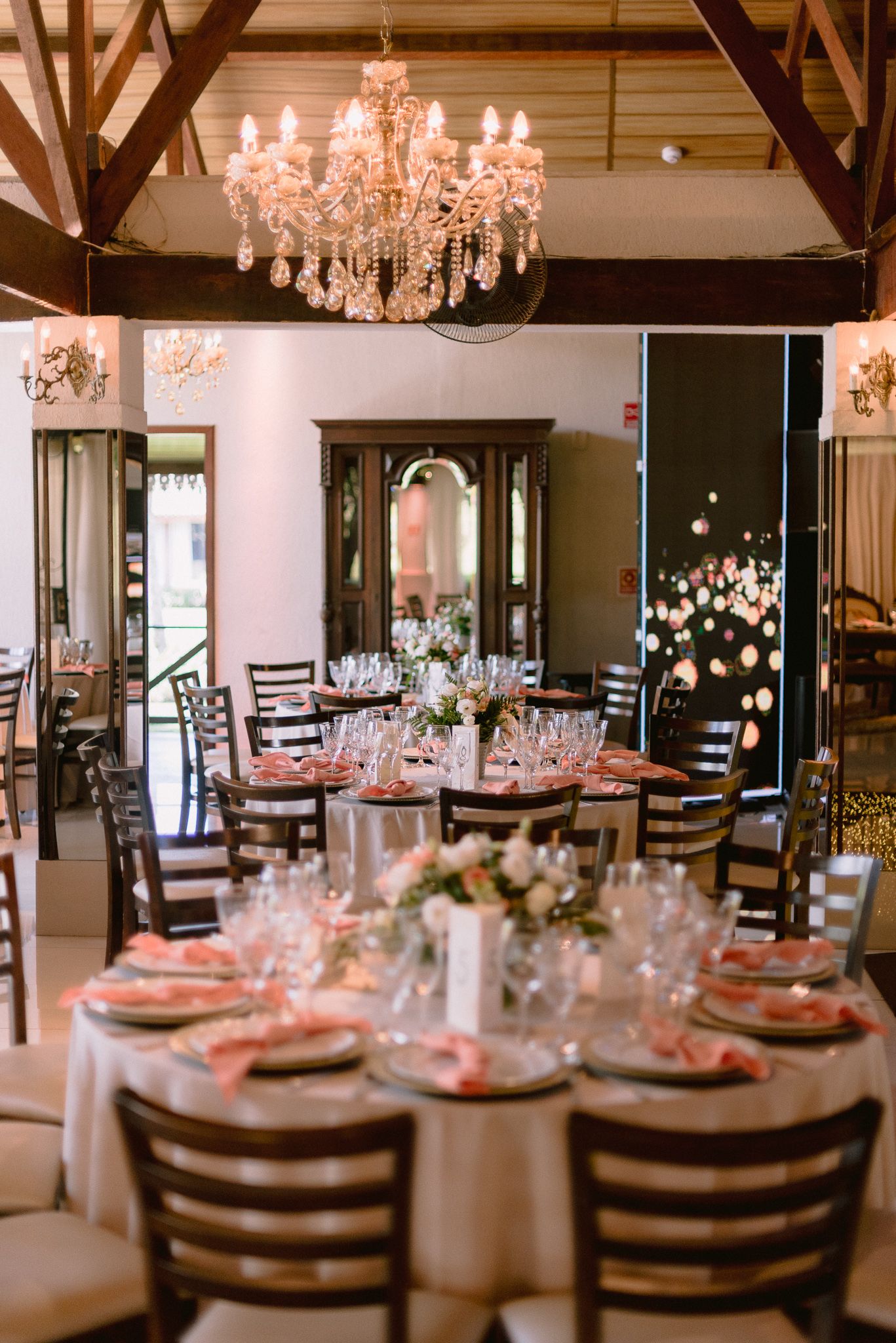 Romantic reception venue with crystal chandeliers and round tables set for an elegant wedding celebration.
