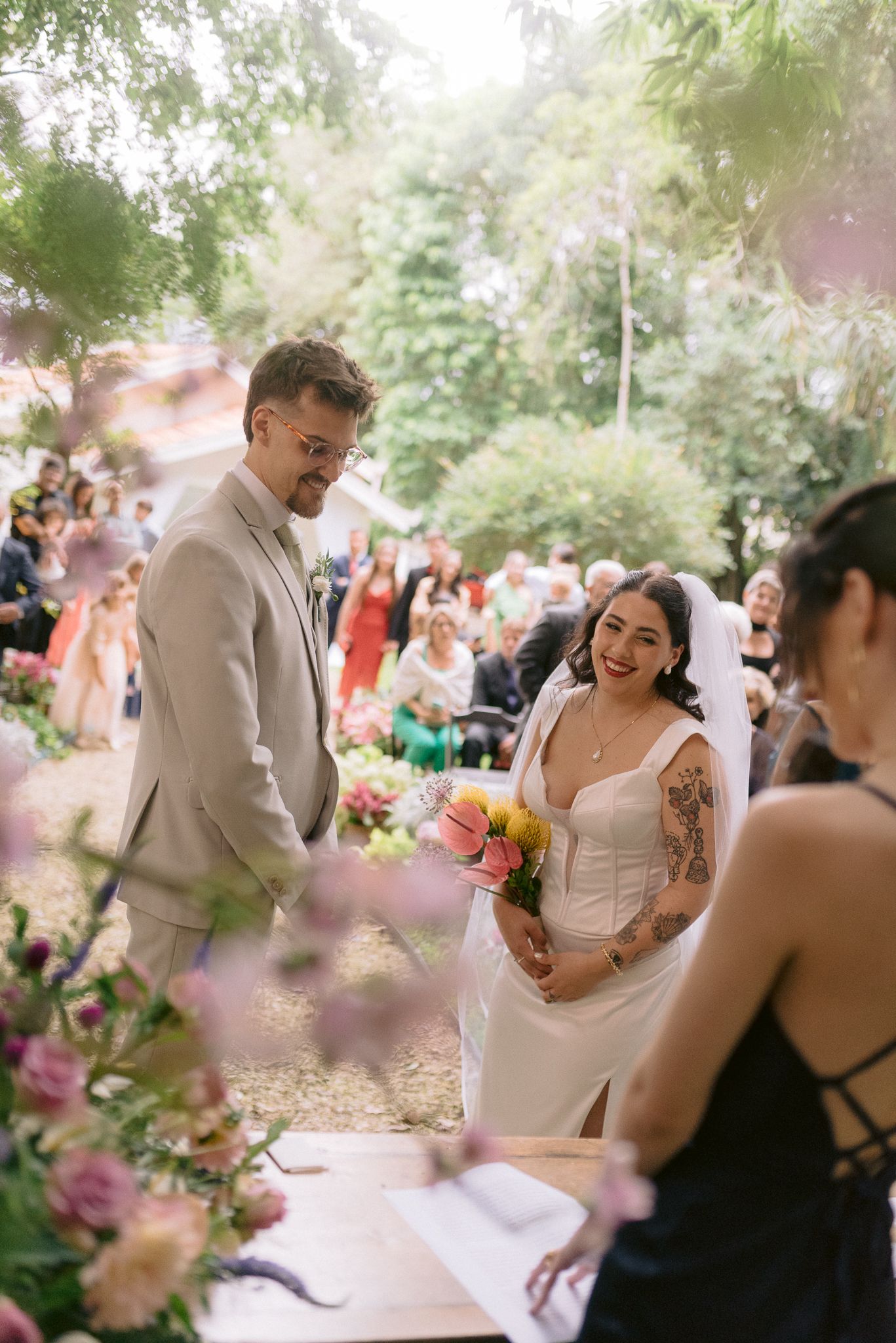 Wedding couple laughs together during their outdoor garden ceremony surrounded by guests.