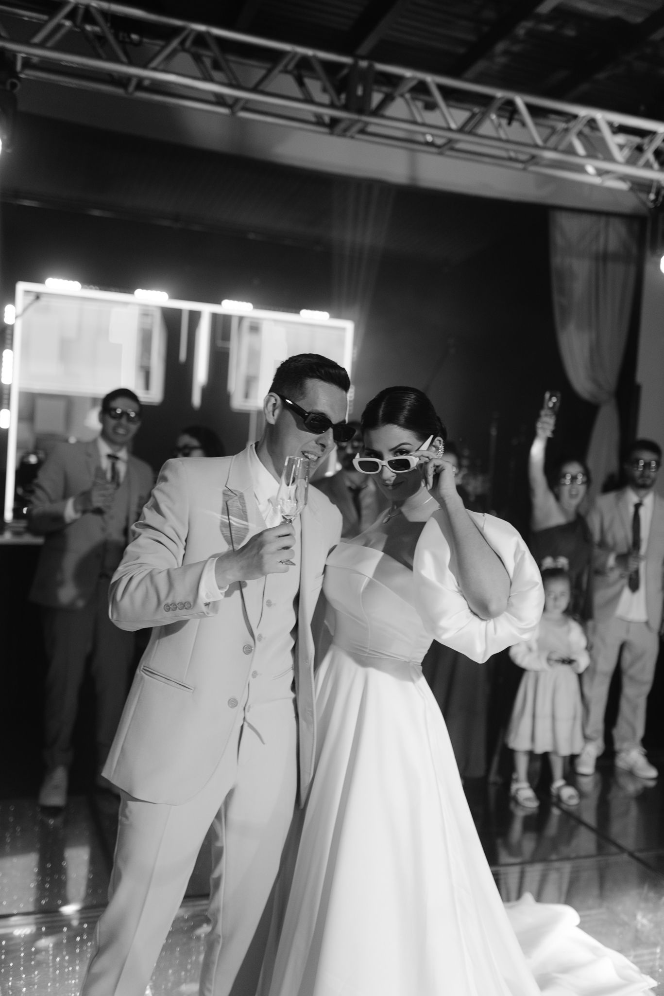 Black and white photo of wedding guests dancing and celebrating at reception party.
