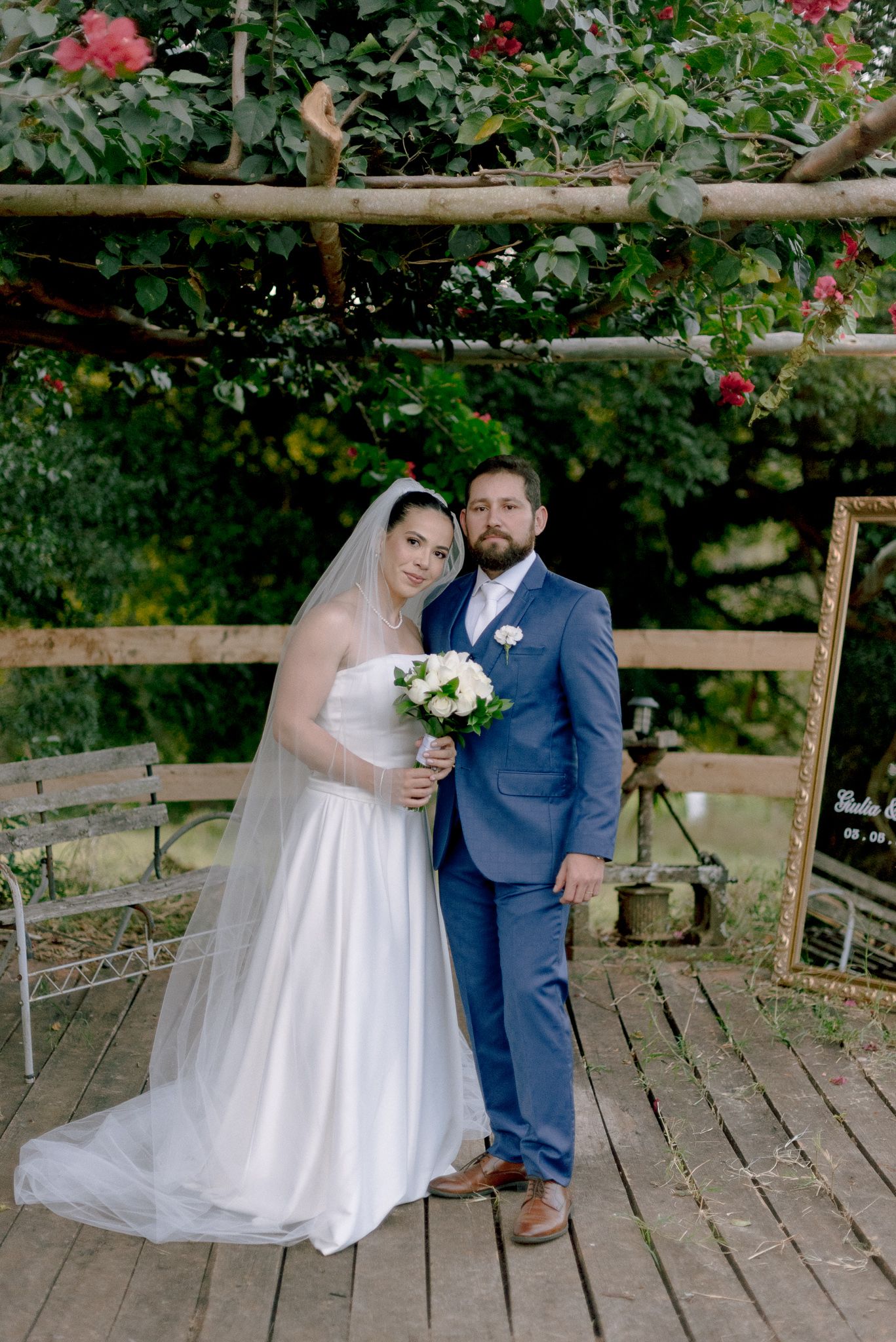 Wooden deck surrounded by lush greenery with red flowers creates a romantic setting for wedding photography.