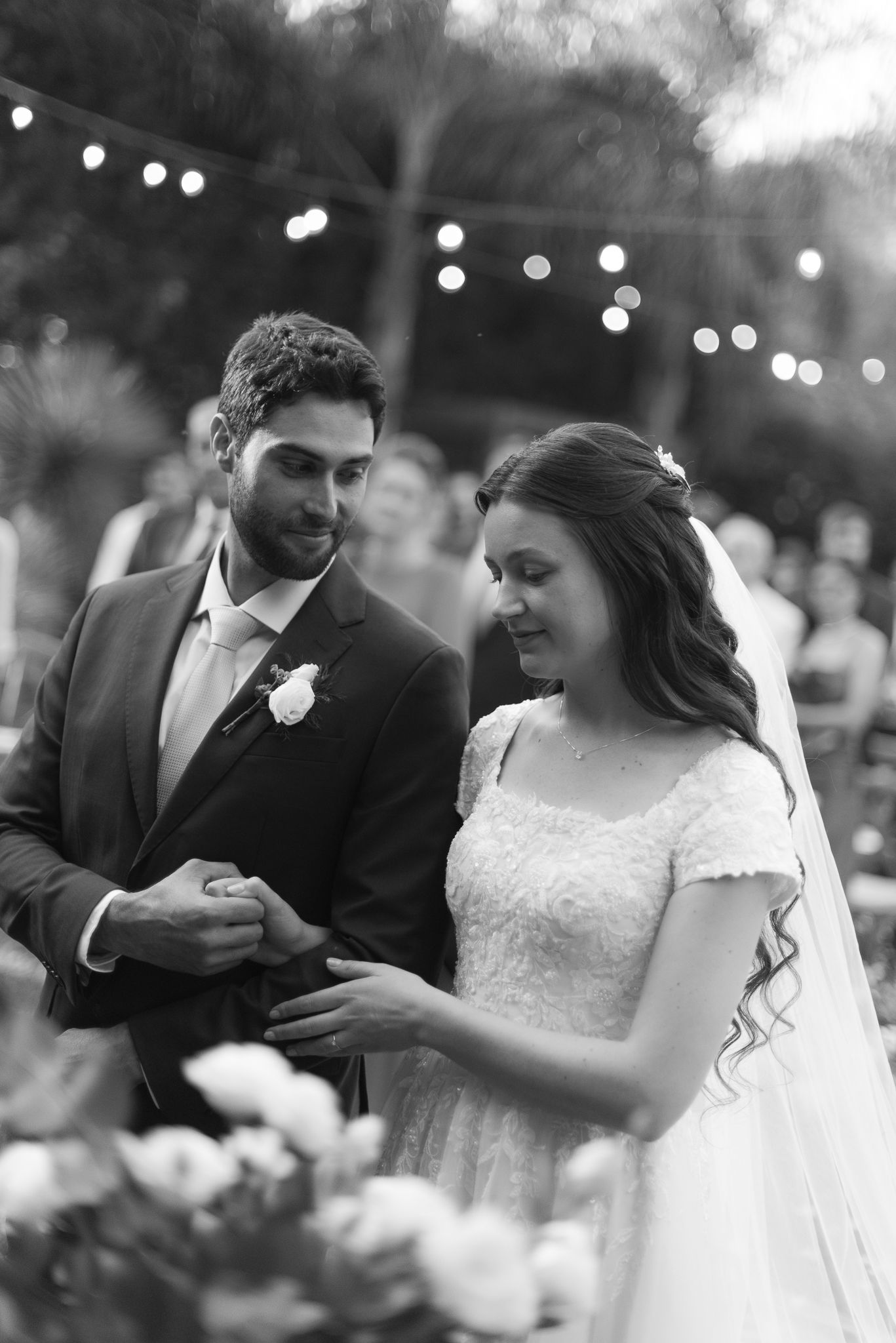 Black and white candid moments from a wedding reception under string lights.