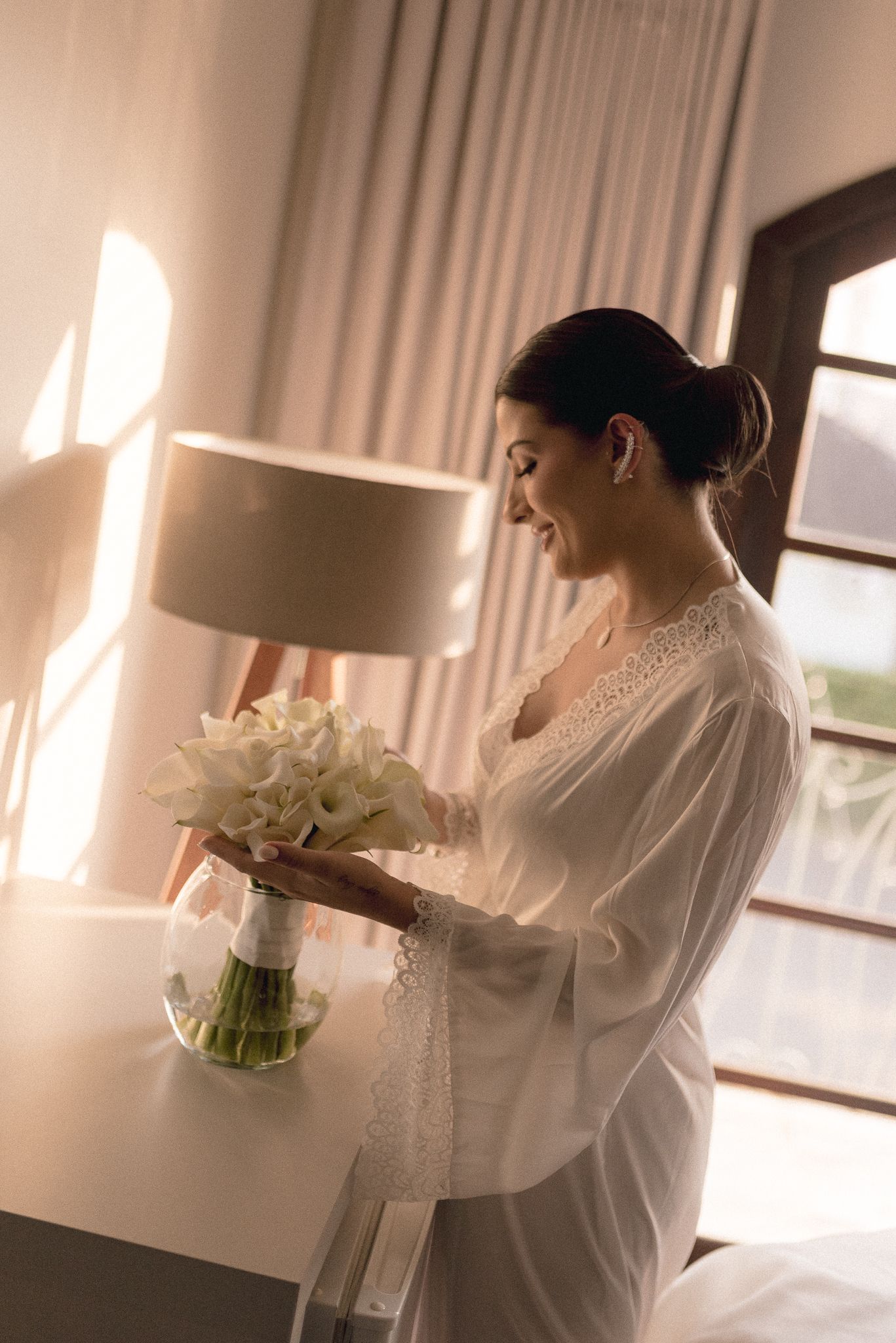 Elegant white bridal robe captured in soft window light during wedding preparations.