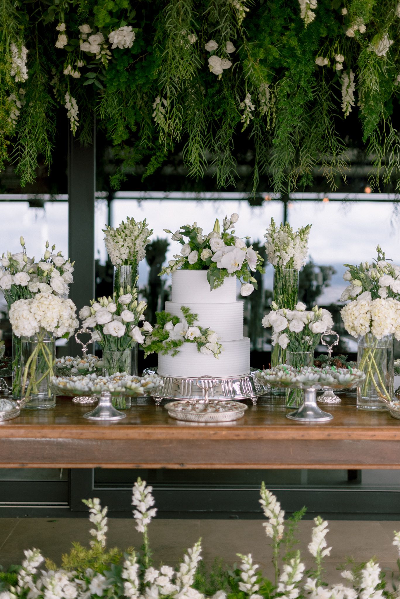 Elegant wedding reception table decorated with white flowers and greenery.