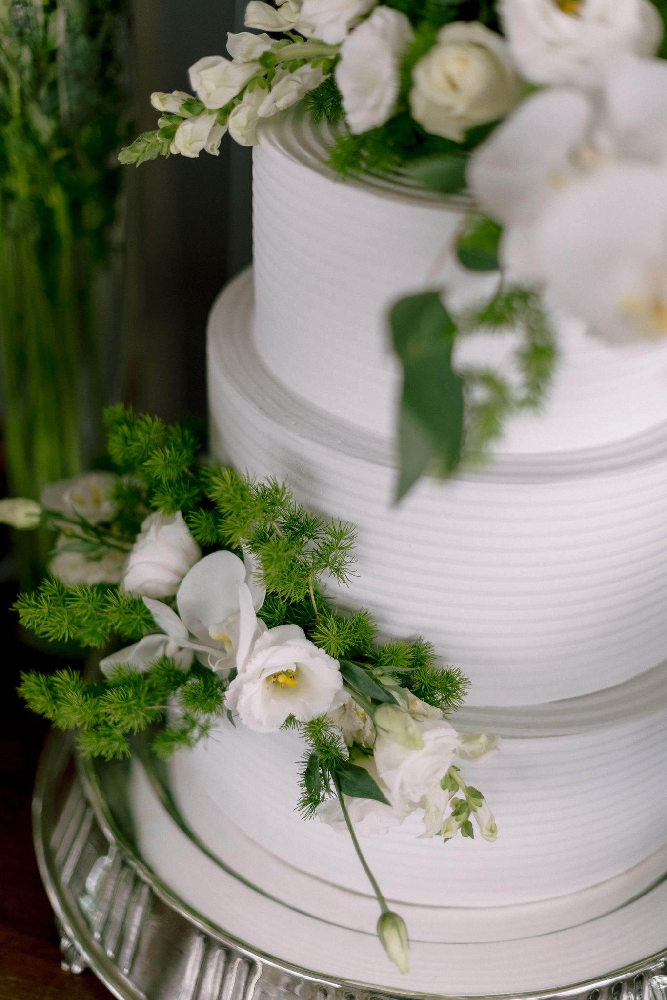 Classic white wedding cake decorated with fresh flowers and greenery.