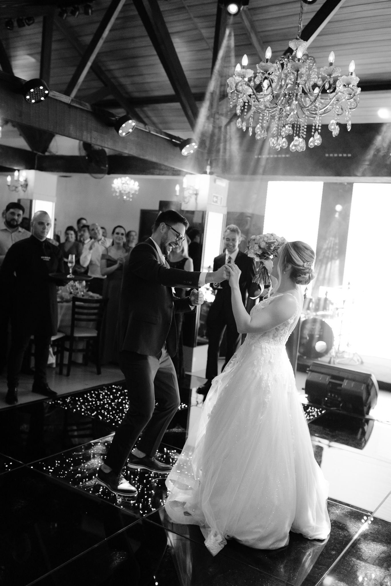 A wedding reception scene in a venue with crystal chandeliers and romantic lighting.