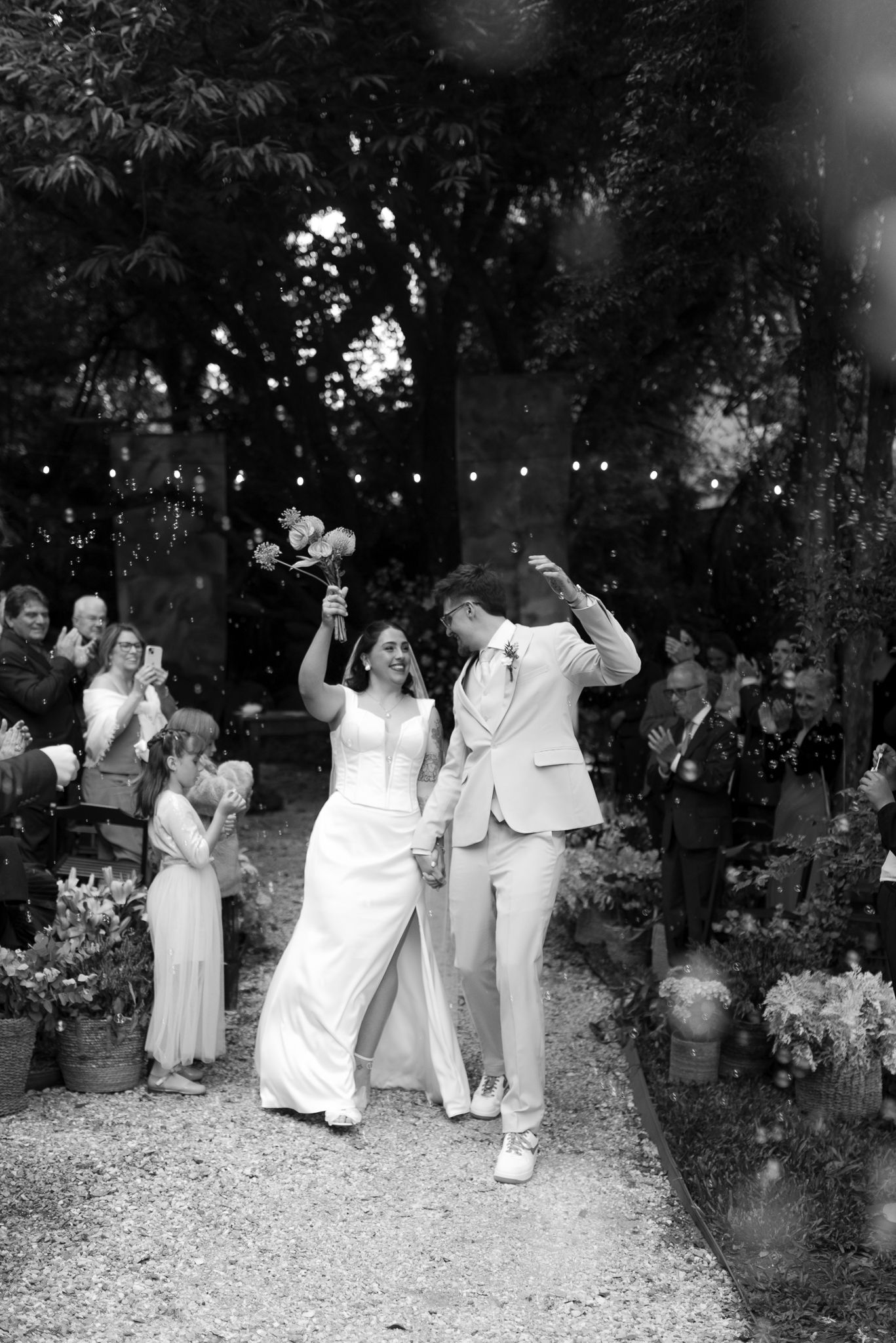 Wedding party in white and tan celebrate outdoors in black and white photography.