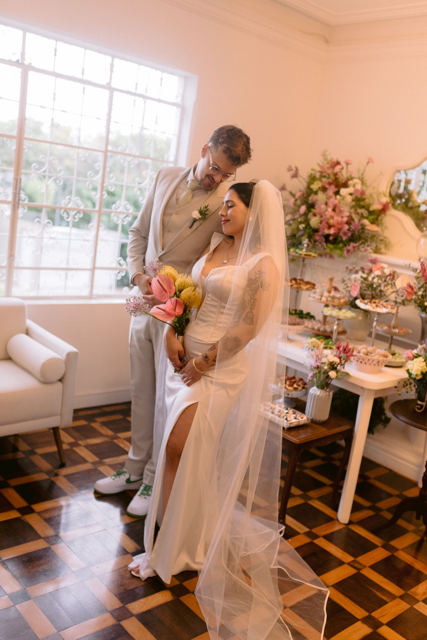 Wedding couple dances in an elegant room with diamond pattern floors and floral decorations.