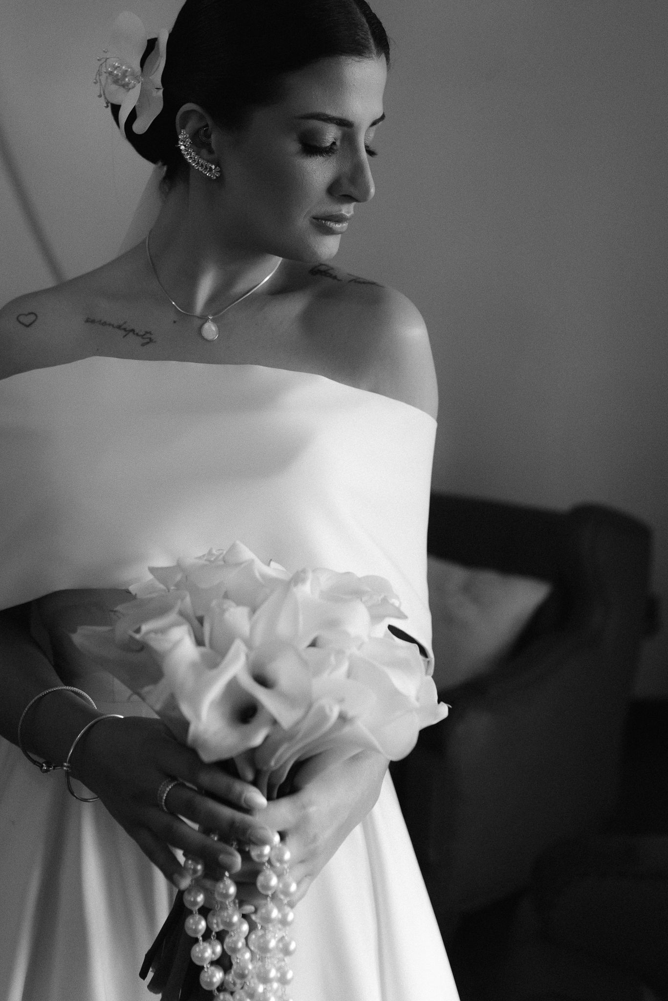 Classic black and white photos capture a bride holding a white bouquet in an off-shoulder wedding dress.