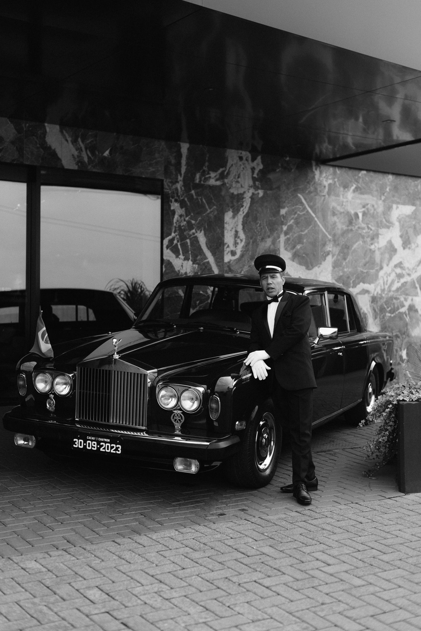 A classic Rolls Royce luxury car with chauffeur in formal attire.