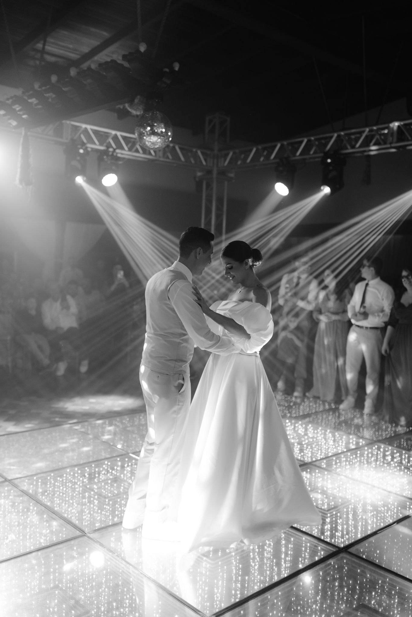 Wedding couple dancing on an illuminated LED dance floor with dramatic lighting effects.