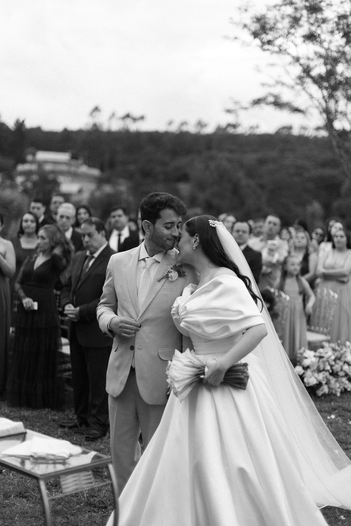 Black and white photo series capturing romantic moments between a bride and groom during an outdoor wedding ceremony.