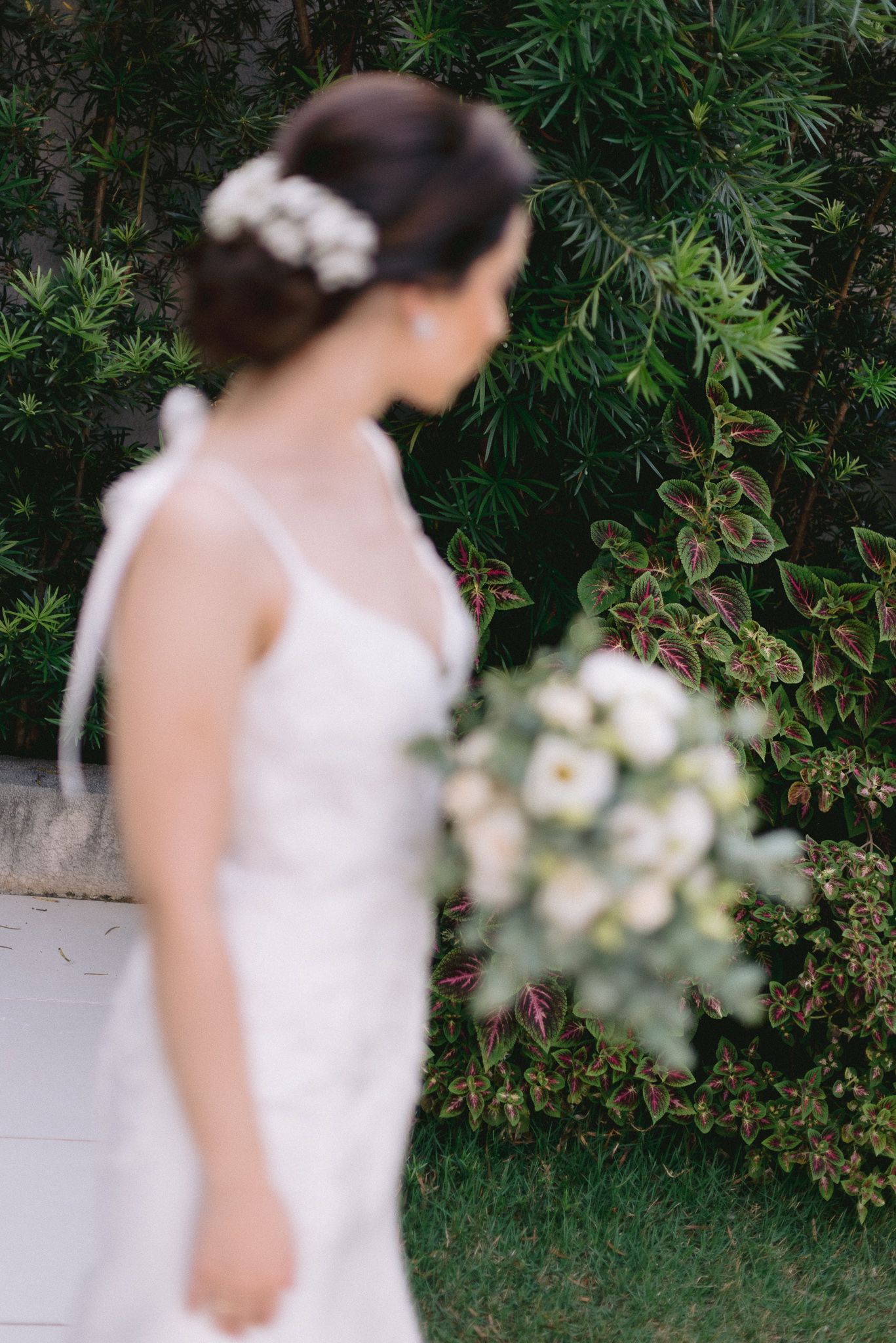 Artistic series of a wedding dress photographed against greenery and white flowers.