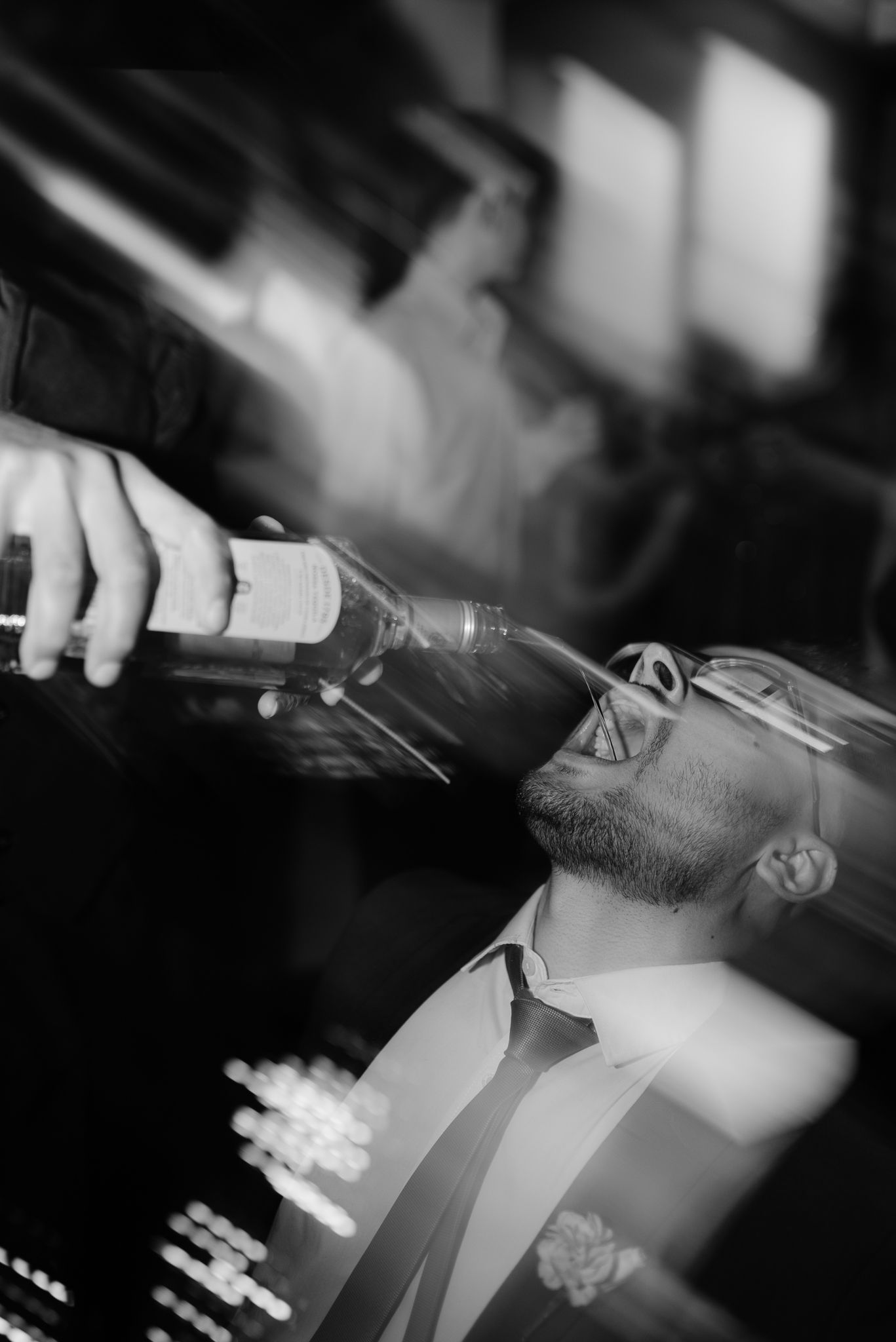 Artistic black and white close-up of someone pouring champagne into glass.