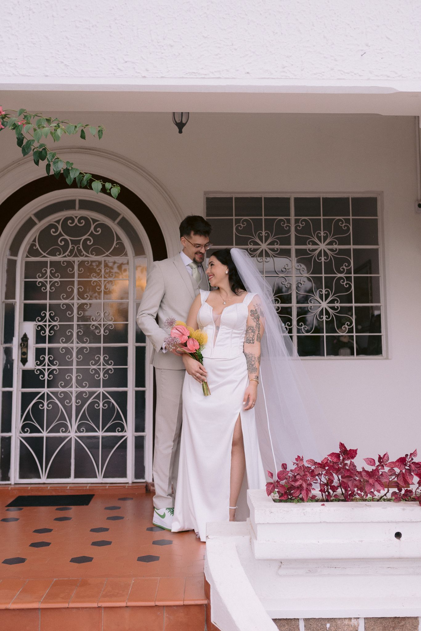 Elegant white house entrance with decorative iron windows and terra cotta steps.