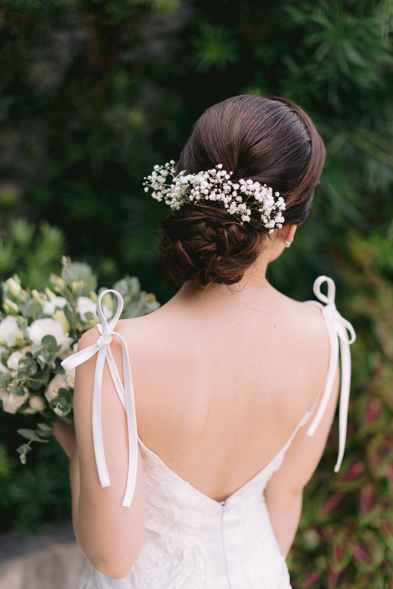 Back view of bridal hairstyle adorned with baby's breath flowers.