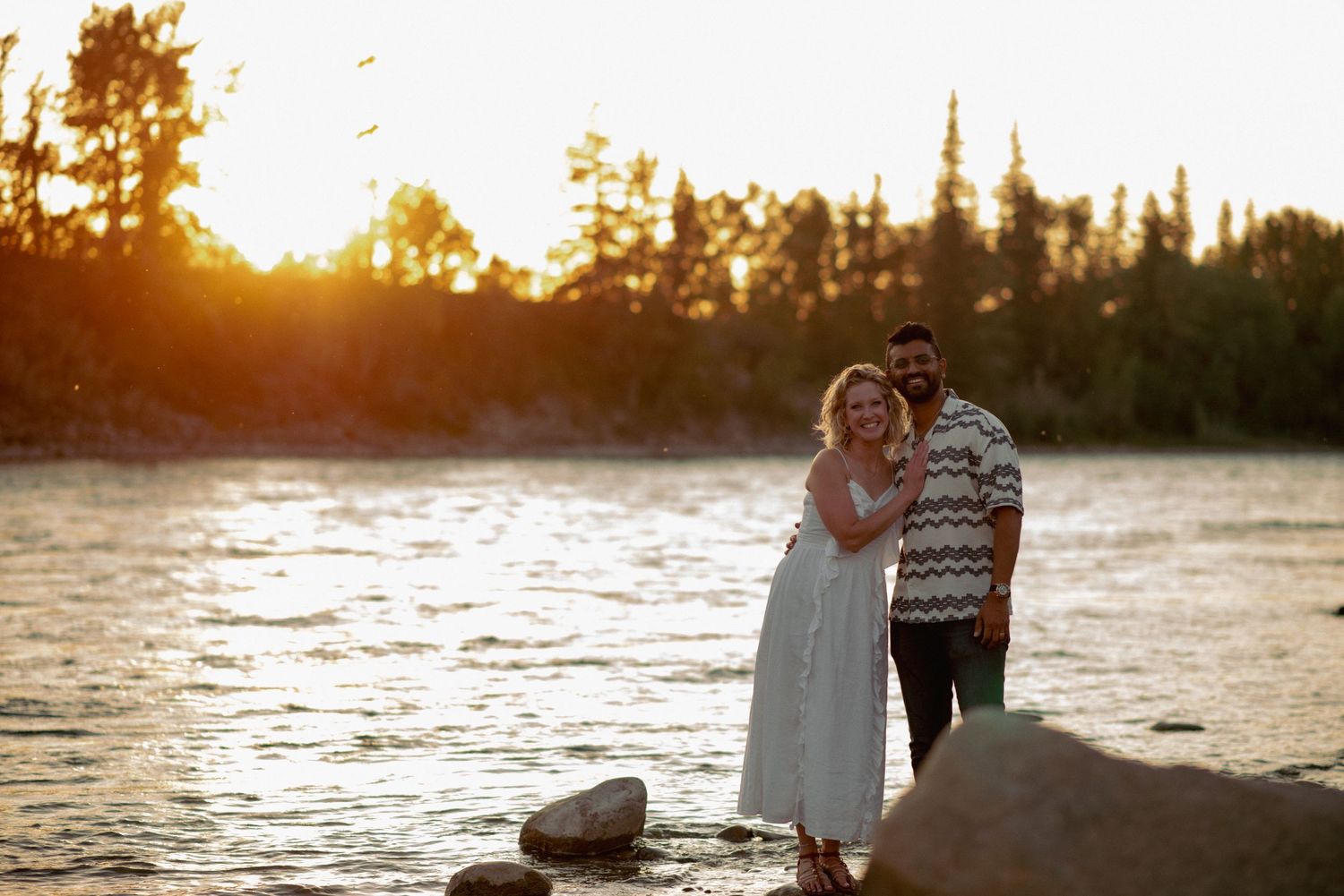 Rocky Mountains Alberta couple photography, intimate posed riverside portrait at golden hour
