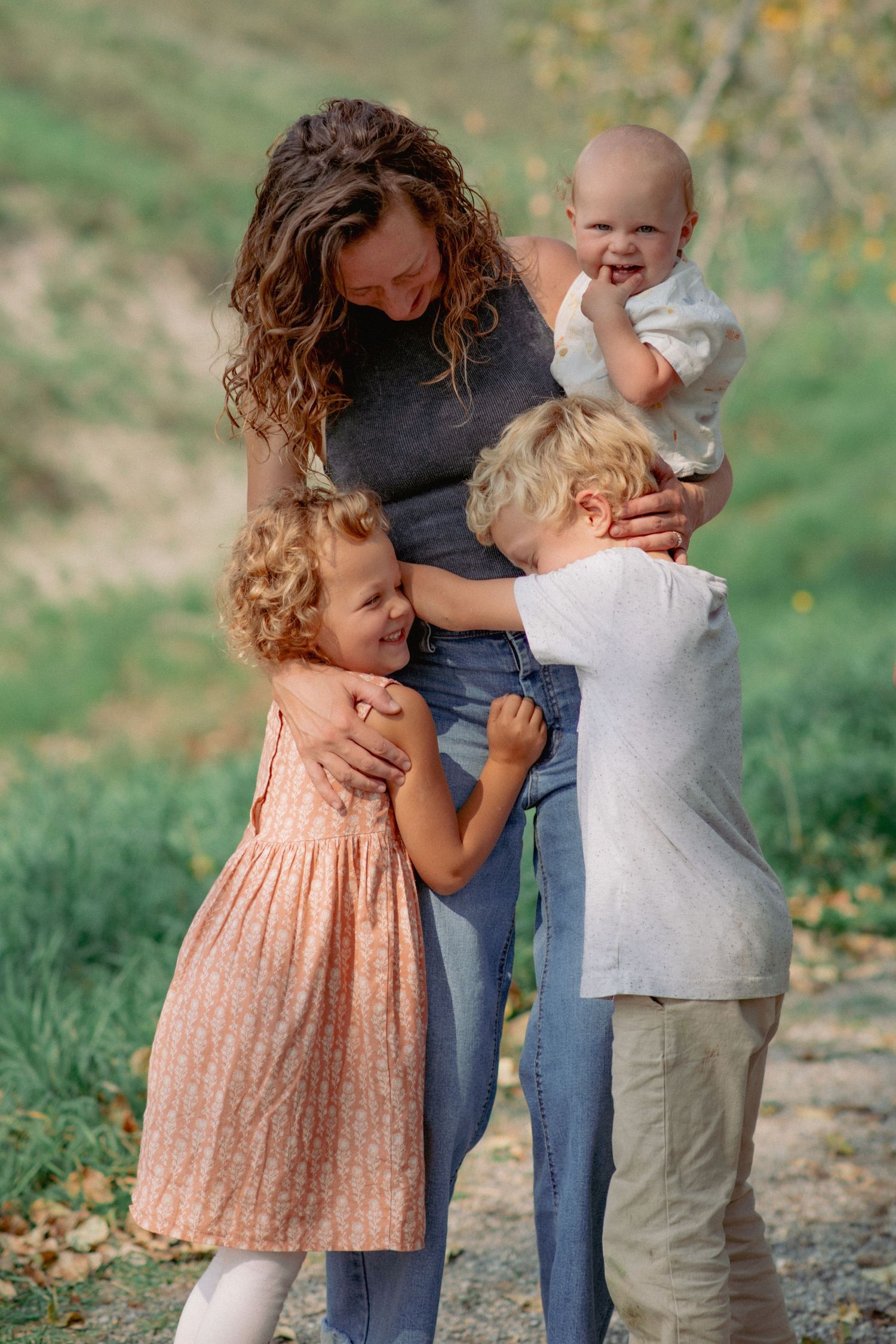 Glenbow Ranch Alberta family photography, mom holding toddler and hugging older children during outdoor session