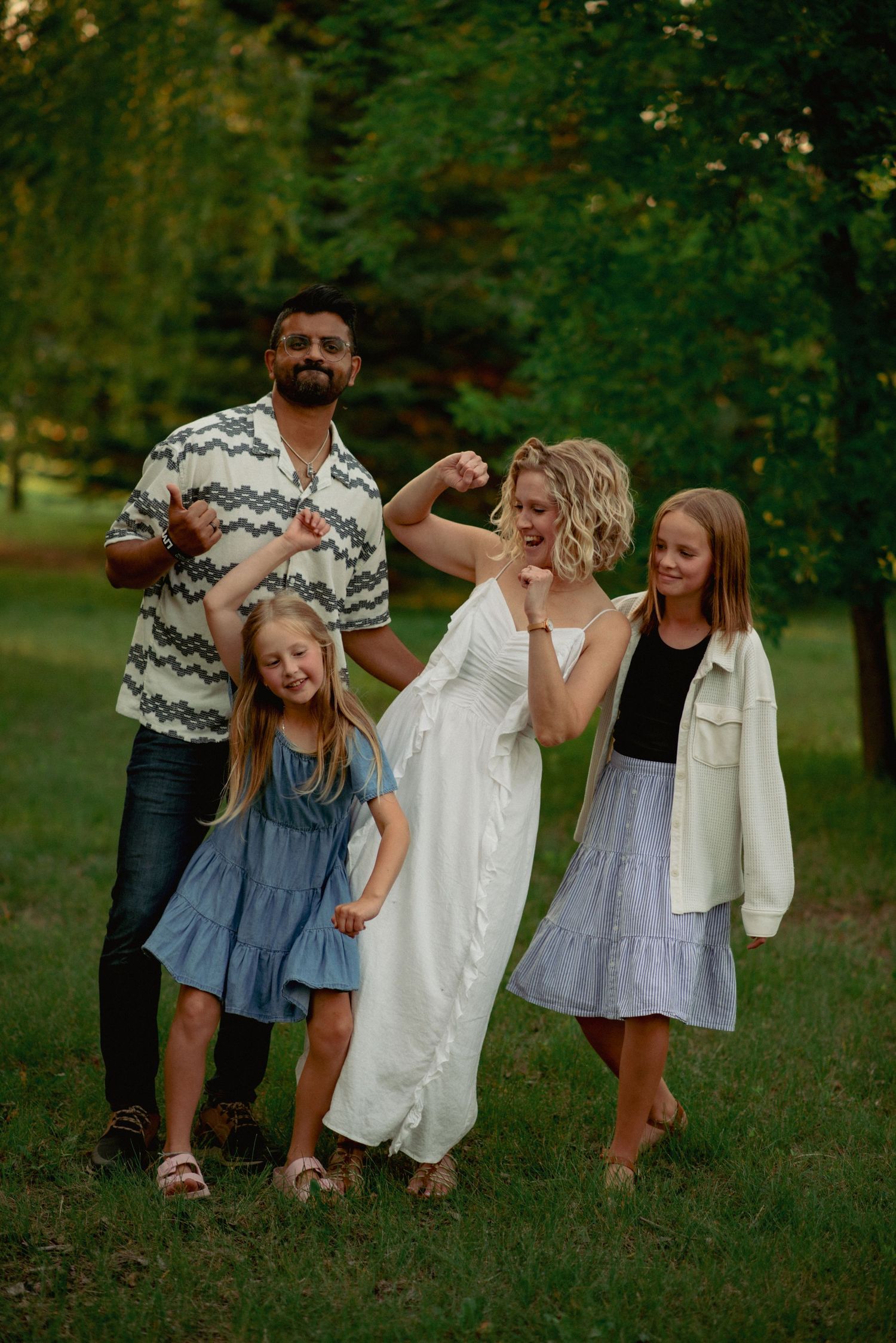 Family dancing together in the Cochrane forest during golden hour photography session