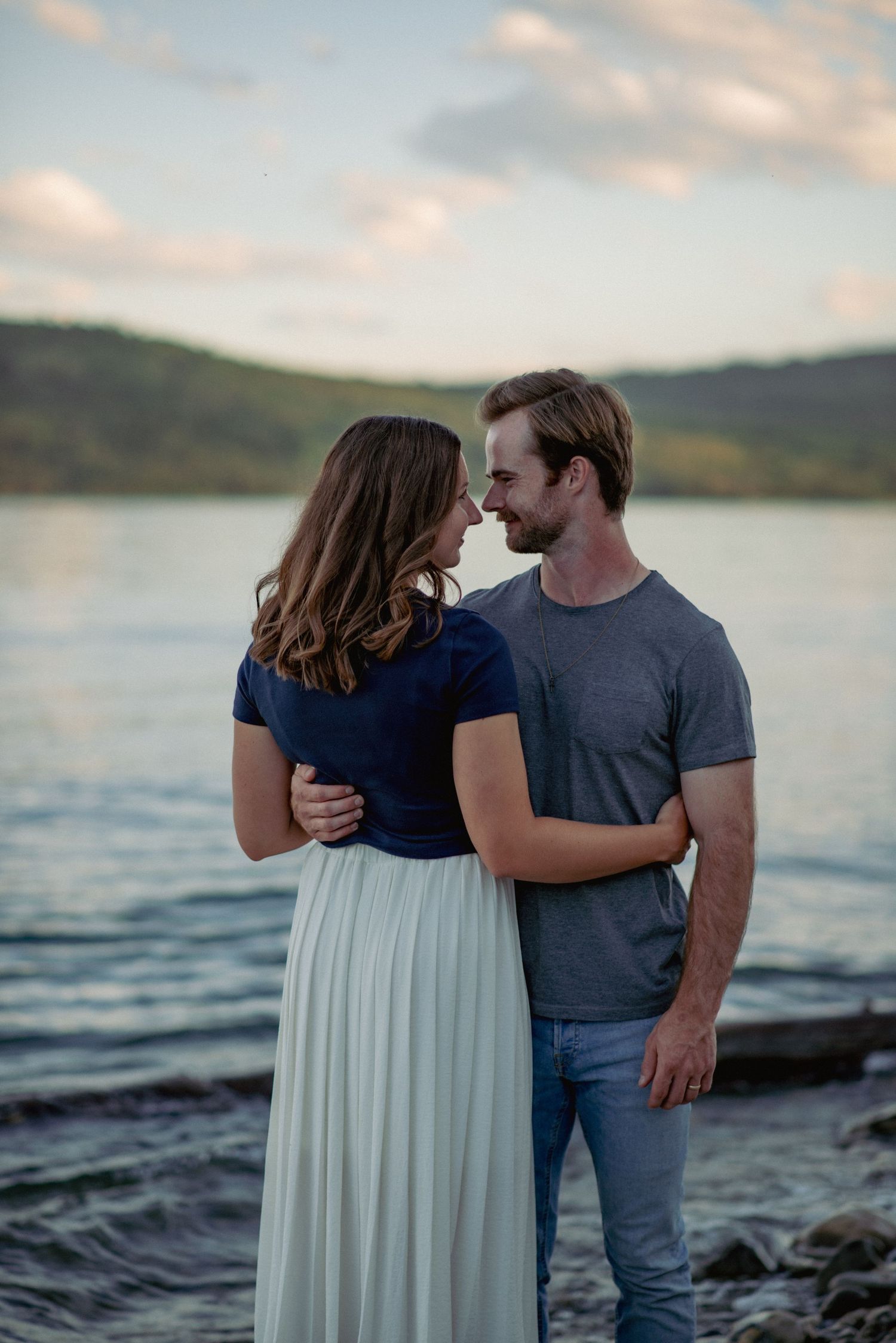 Couple photography Ghost Lake Alberta, partners embracing in front of scenic waters during outdoor session