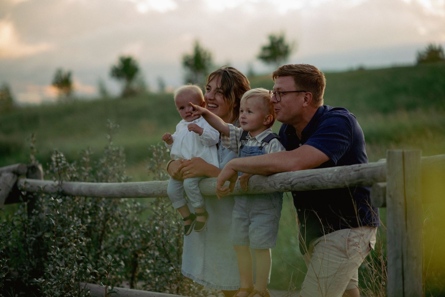Outdoor family photoshoot in Cochrane, Alberta with parents and children pointing at mountain views