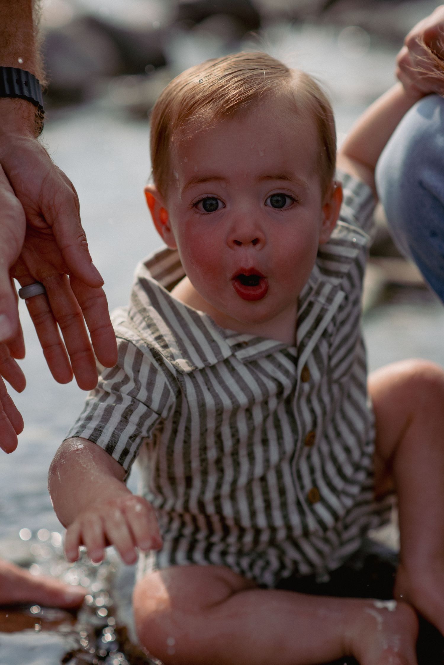 Bragg Creek family photography, one-year-old boy splashing in river waters during outdoor session
