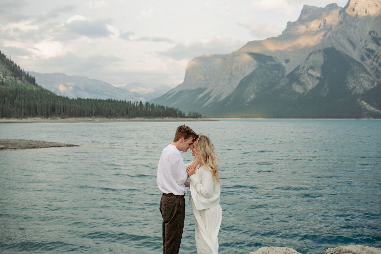 Couple photography Rocky Mountains Alberta, intimate moment shared in front of scenic mountain backdrop