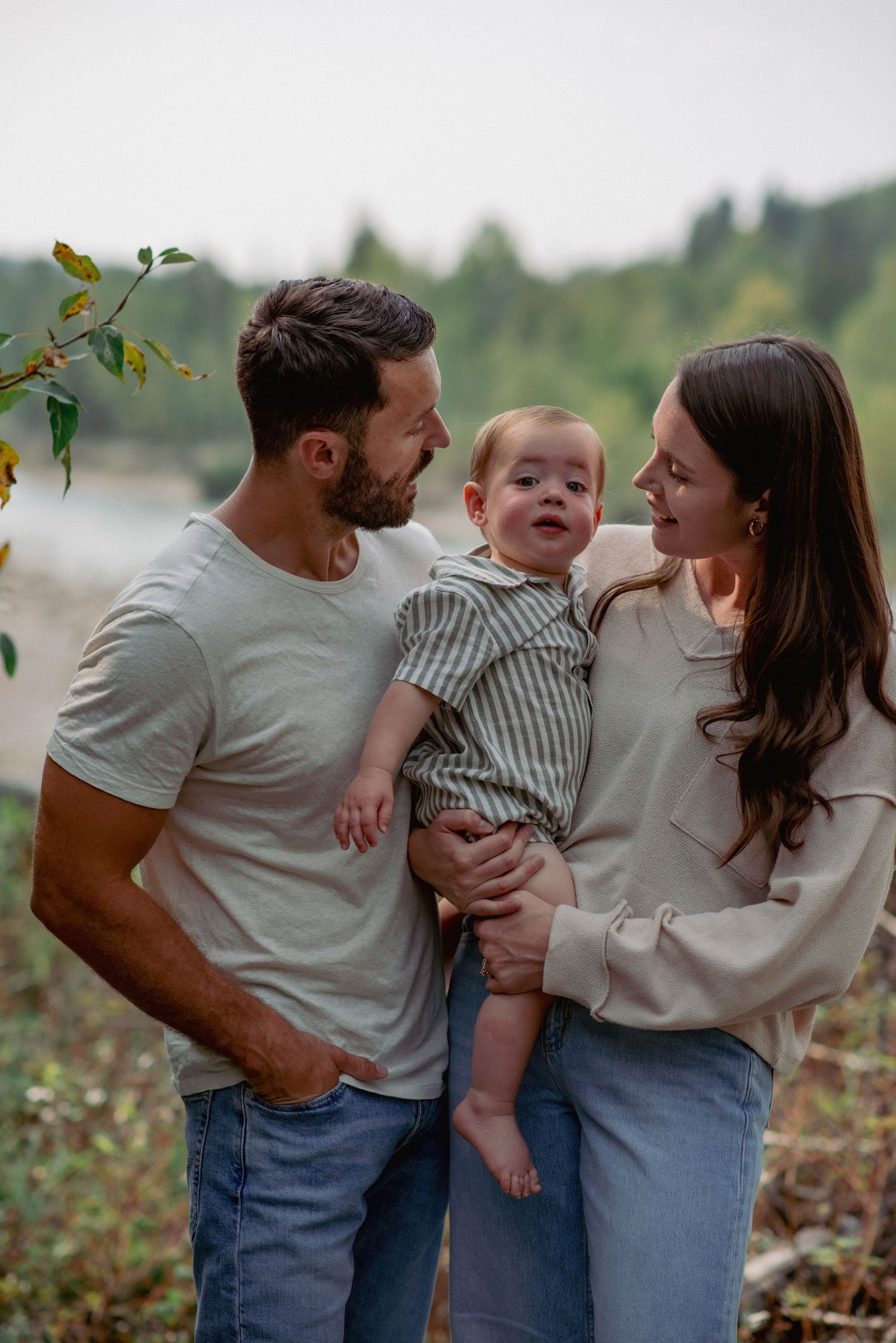 amily photography in the Rocky Mountains Alberta, mom holding toddler son on hip with parents looking at him