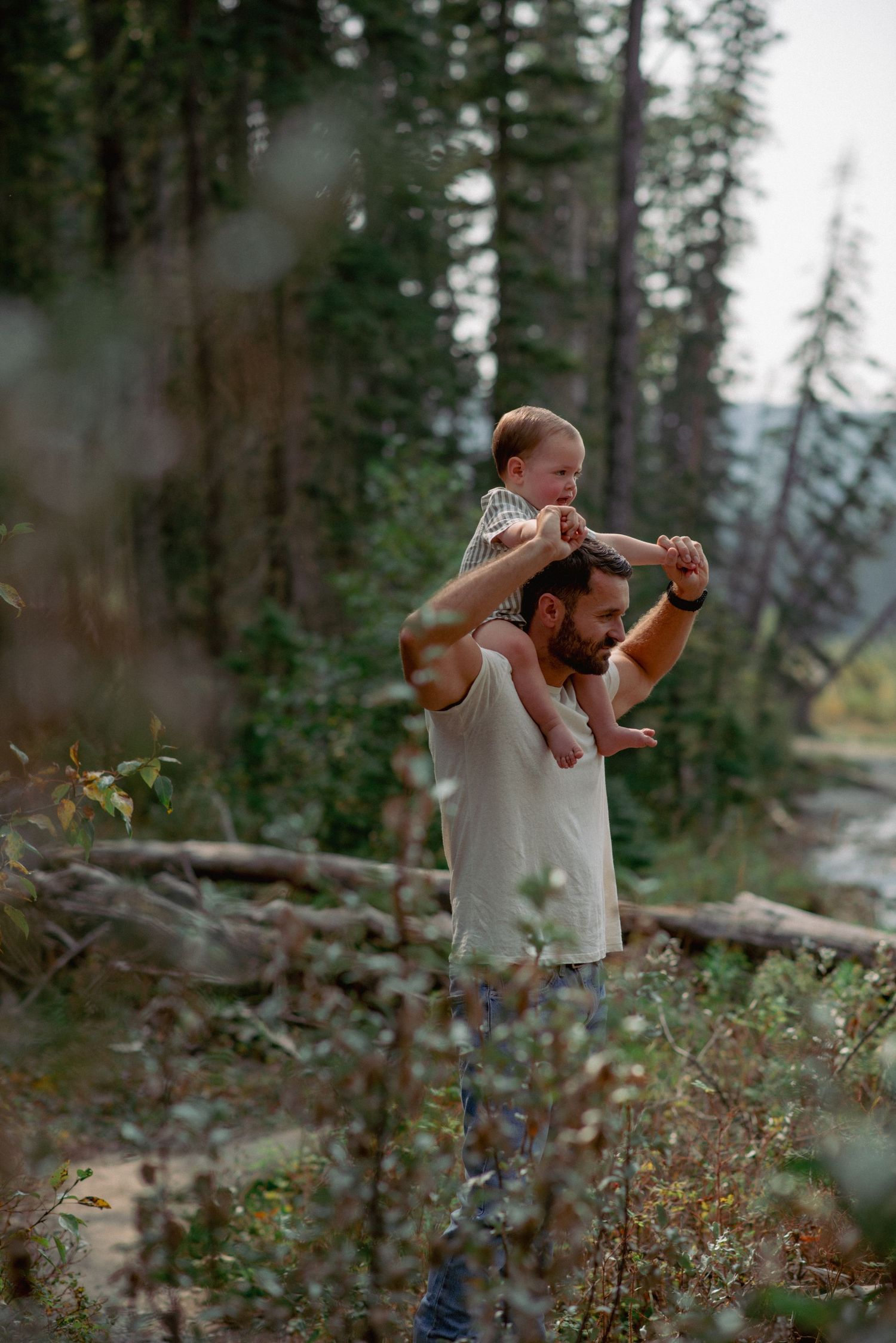 Forest family photos Rocky Mountains Alberta, playful toddler riding dad’s shoulders during session