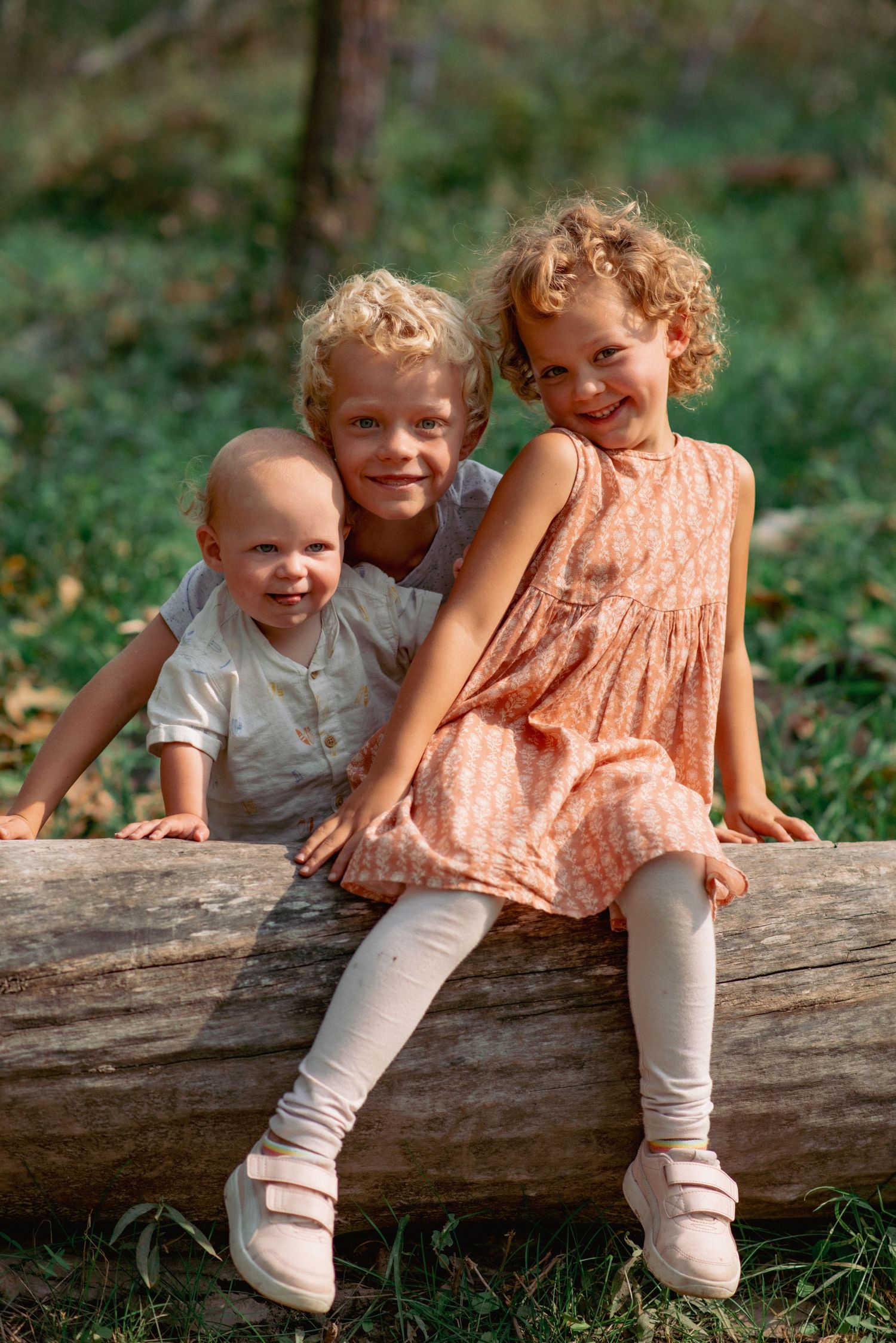 Glenbow Ranch Alberta family photography, siblings smiling together on log in scenic park