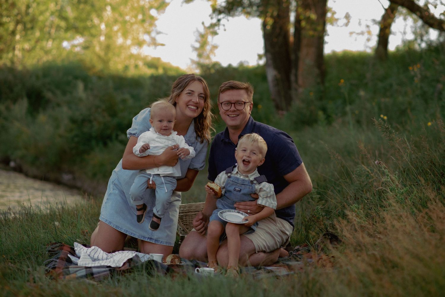 Lifestyle family photography in Cochrane, Alberta, parents and kids sitting on a blanket having a picnic