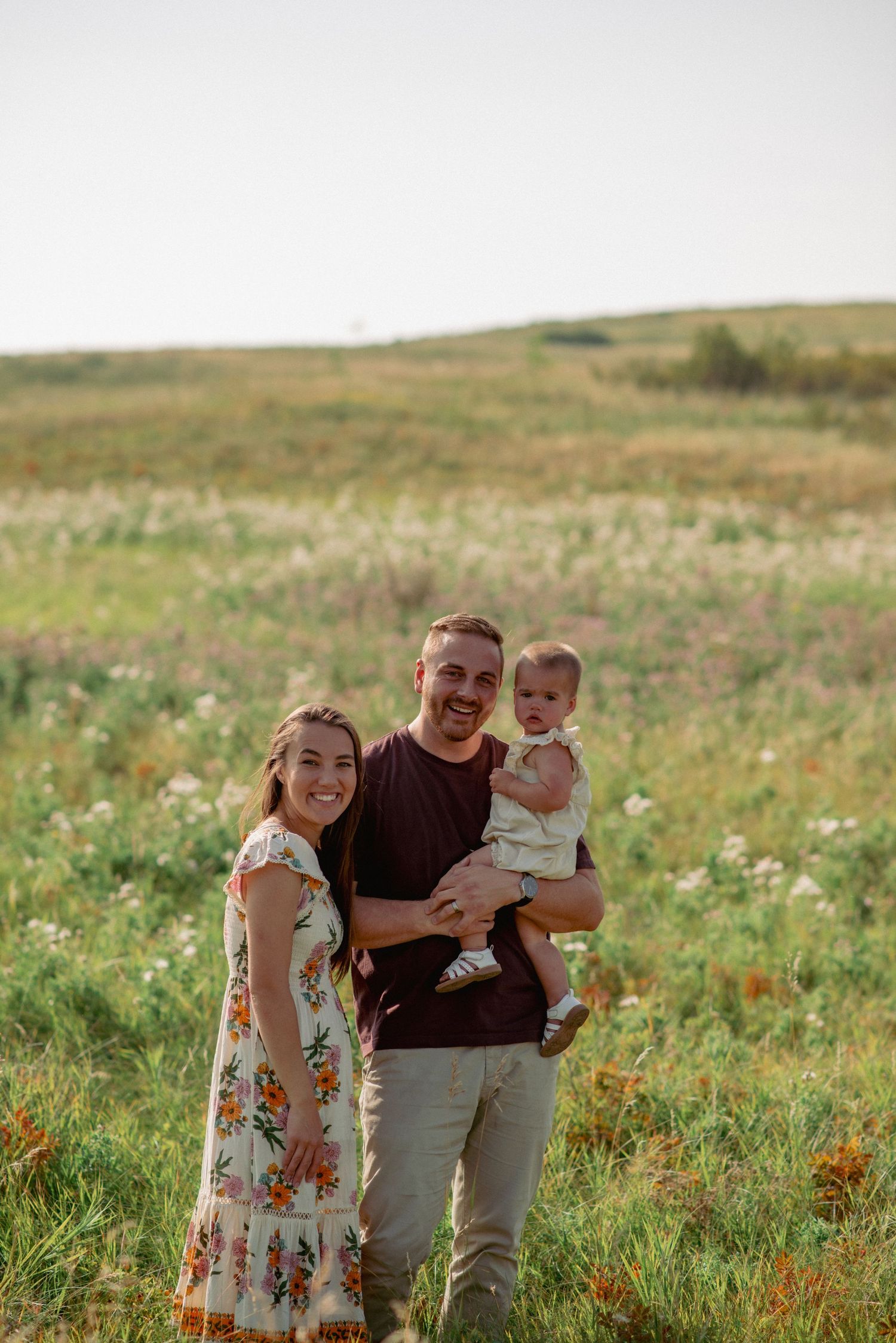 Candid-style posed family portrait Calgary, parents with baby girl in Nose Hill Park