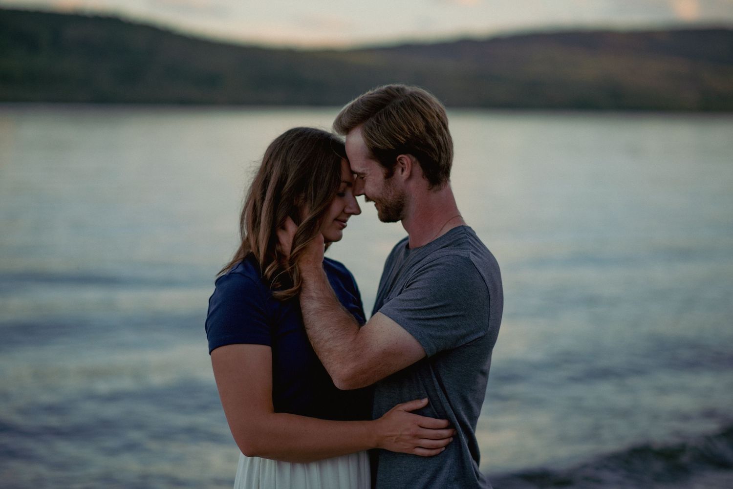 Couple photography Ghost Lake Alberta, partners embracing in front of scenic waters during outdoor session