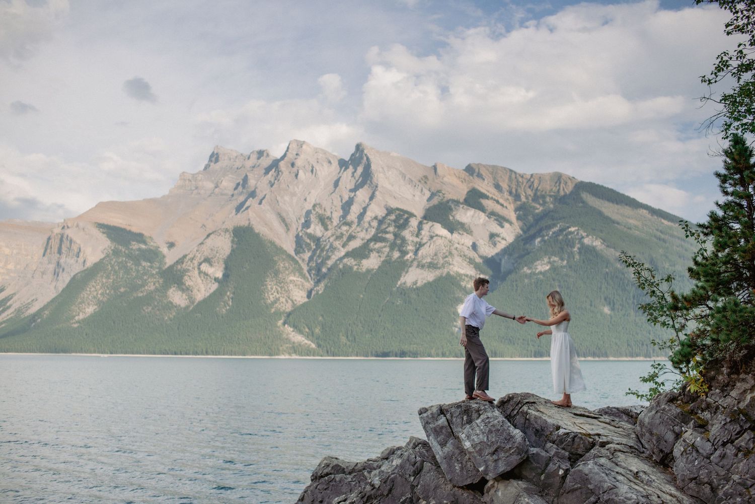 Outdoor engagement session Rocky Mountains Alberta, couple dancing at Lake Minnewanka with scenic mountains