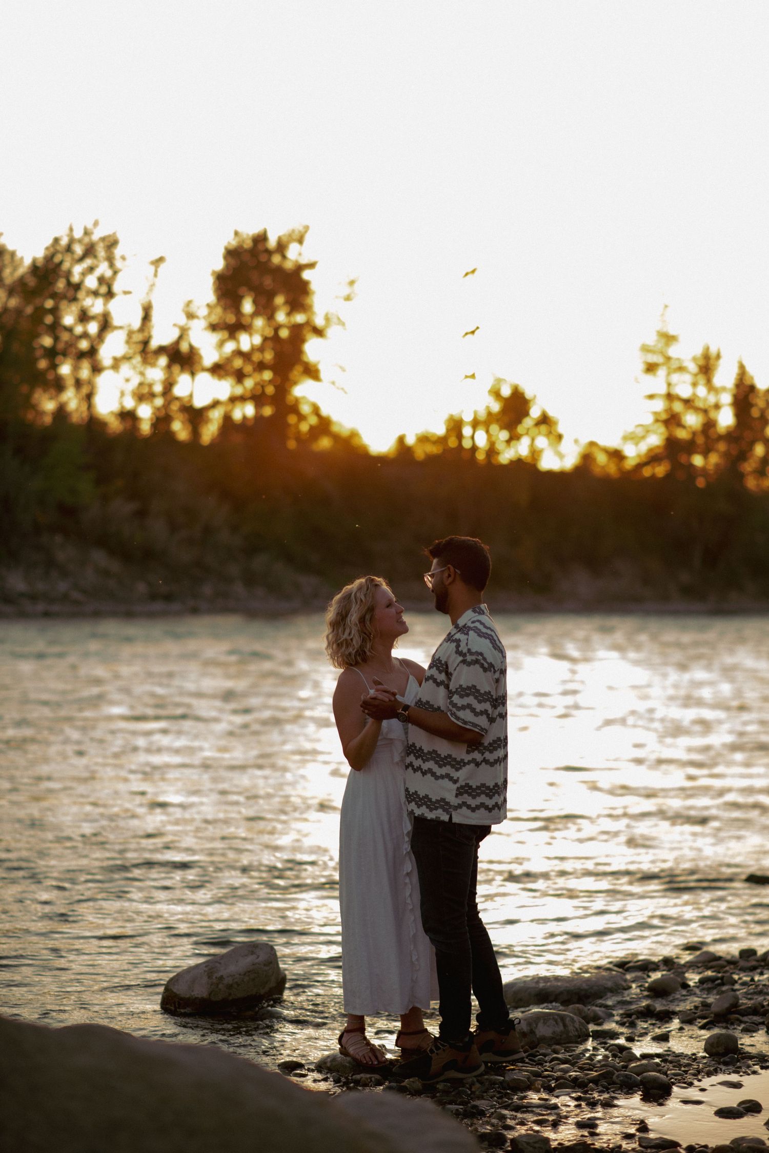 Professional couple photos Alberta, partners dancing at sunset by scenic river