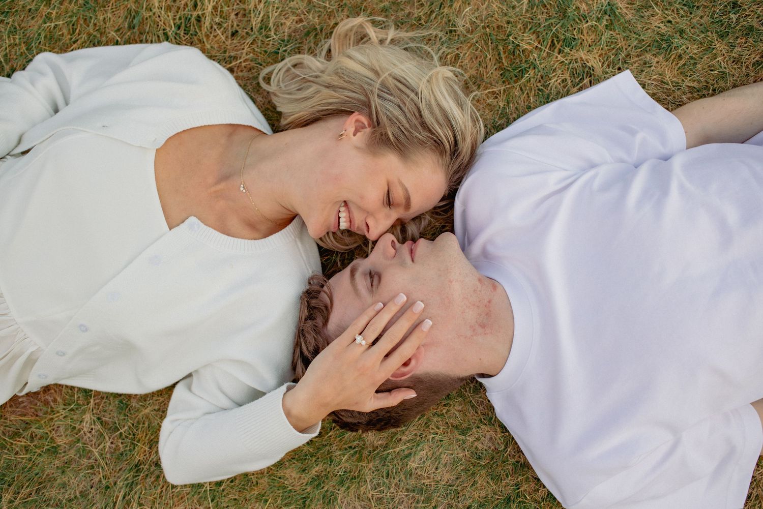 Candid couples photography Rocky Mountains, couple sharing intimate moment lying in outdoor field