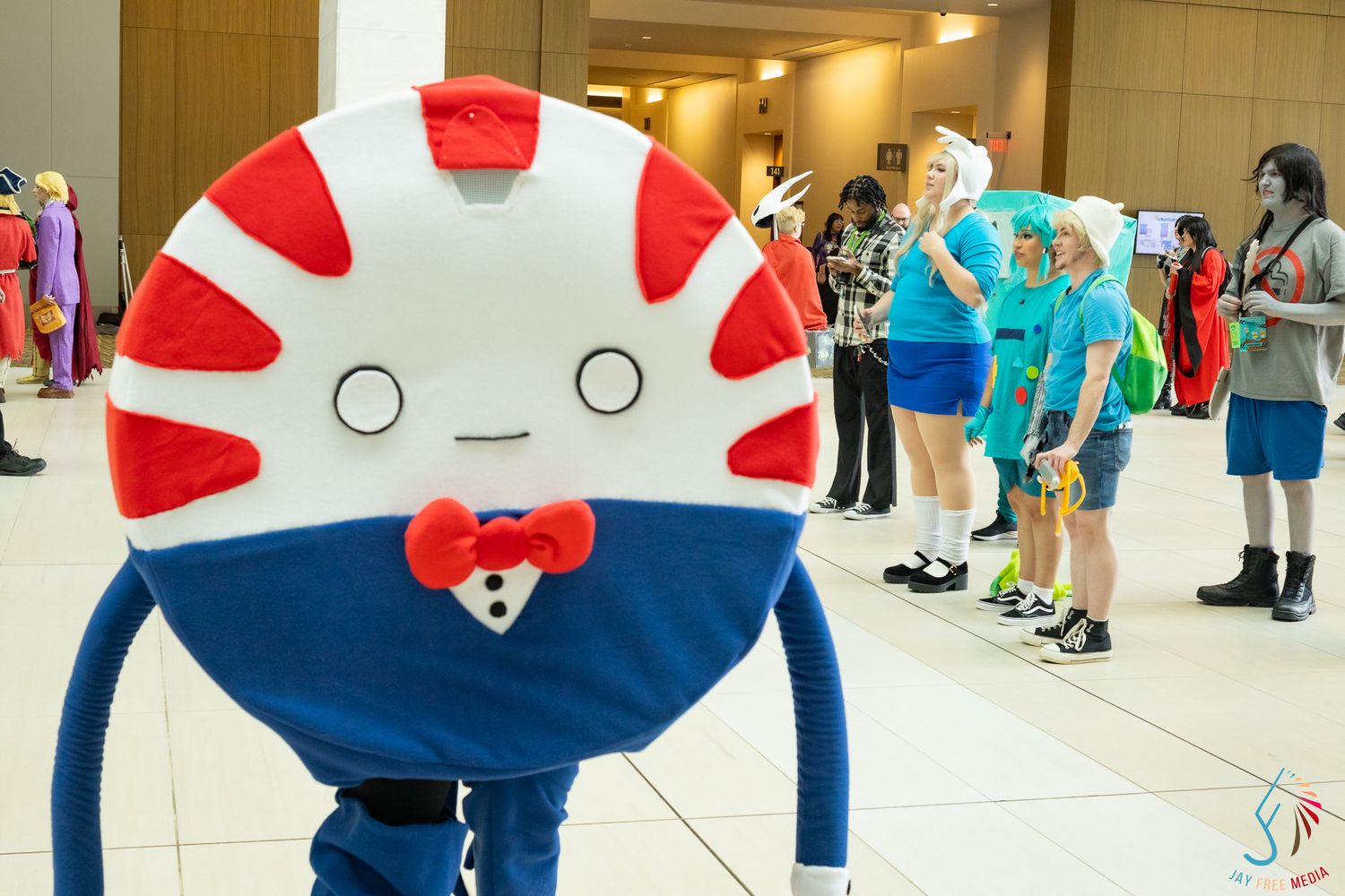 Peppermint Butler and Adventure Time cosplayers gather in bright convention center lobby.
