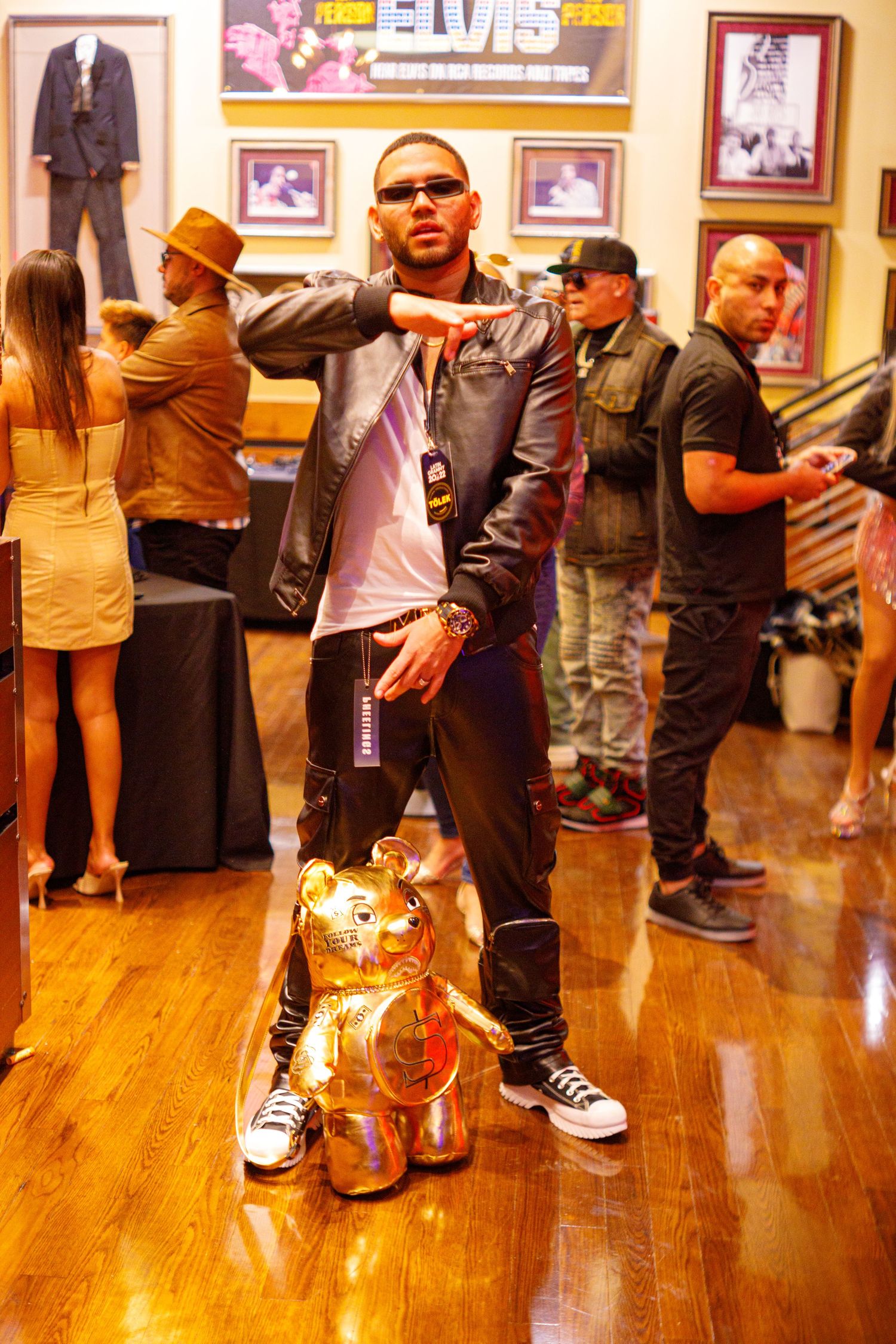 Man posing with gold bear statue inside Hard Rock Cafe with Elvis memorabilia displayed on walls.