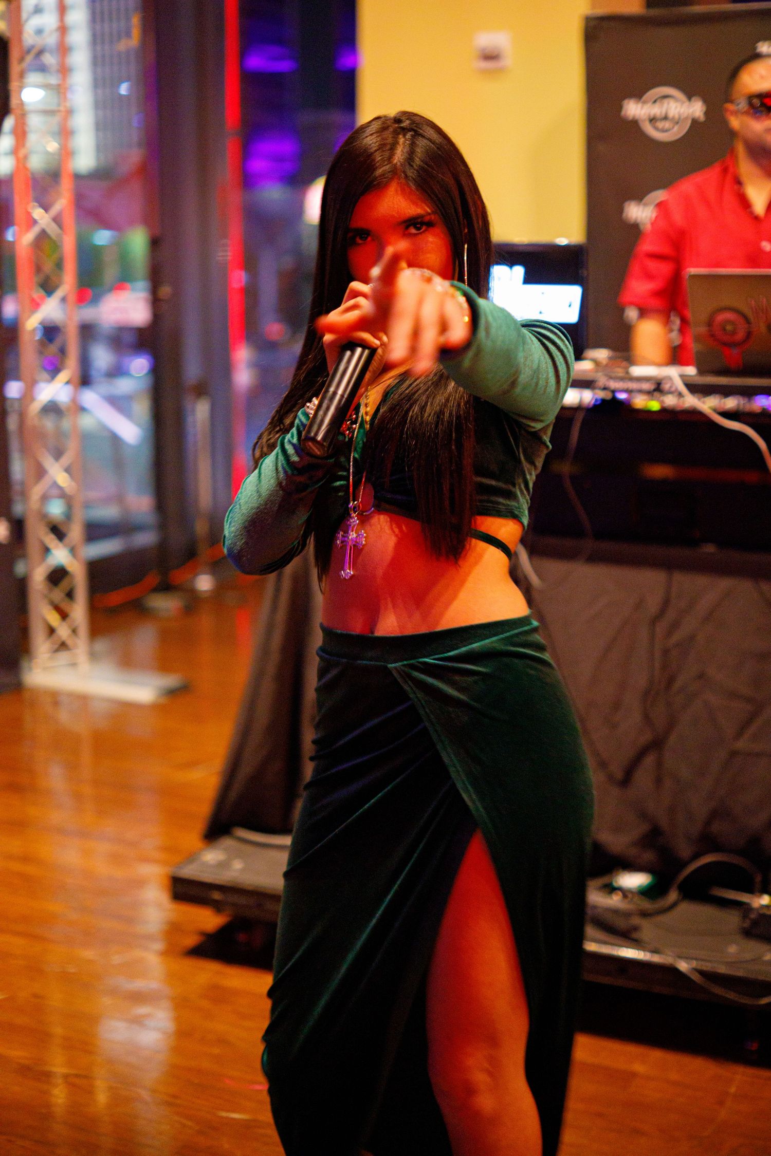 A female performer in a green velvet outfit sings into a microphone at a Hard Rock Cafe venue.