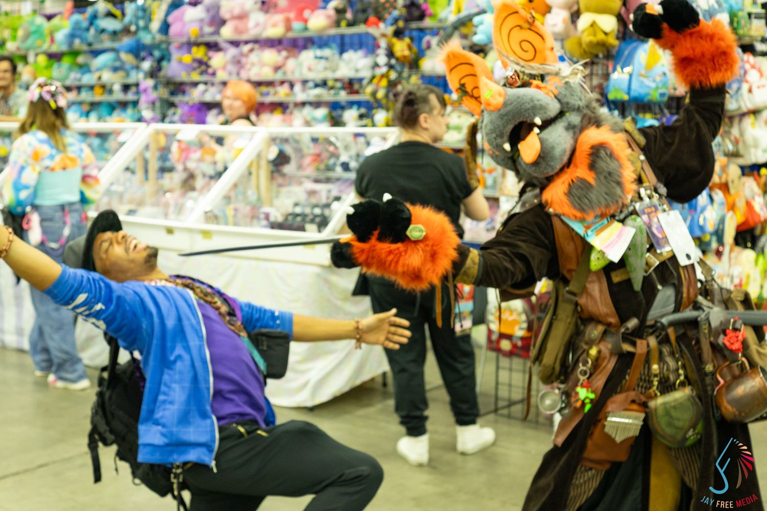 Cosplayer dramatically poses with a furry puppet character in a colorful vendor hall at an anime convention.