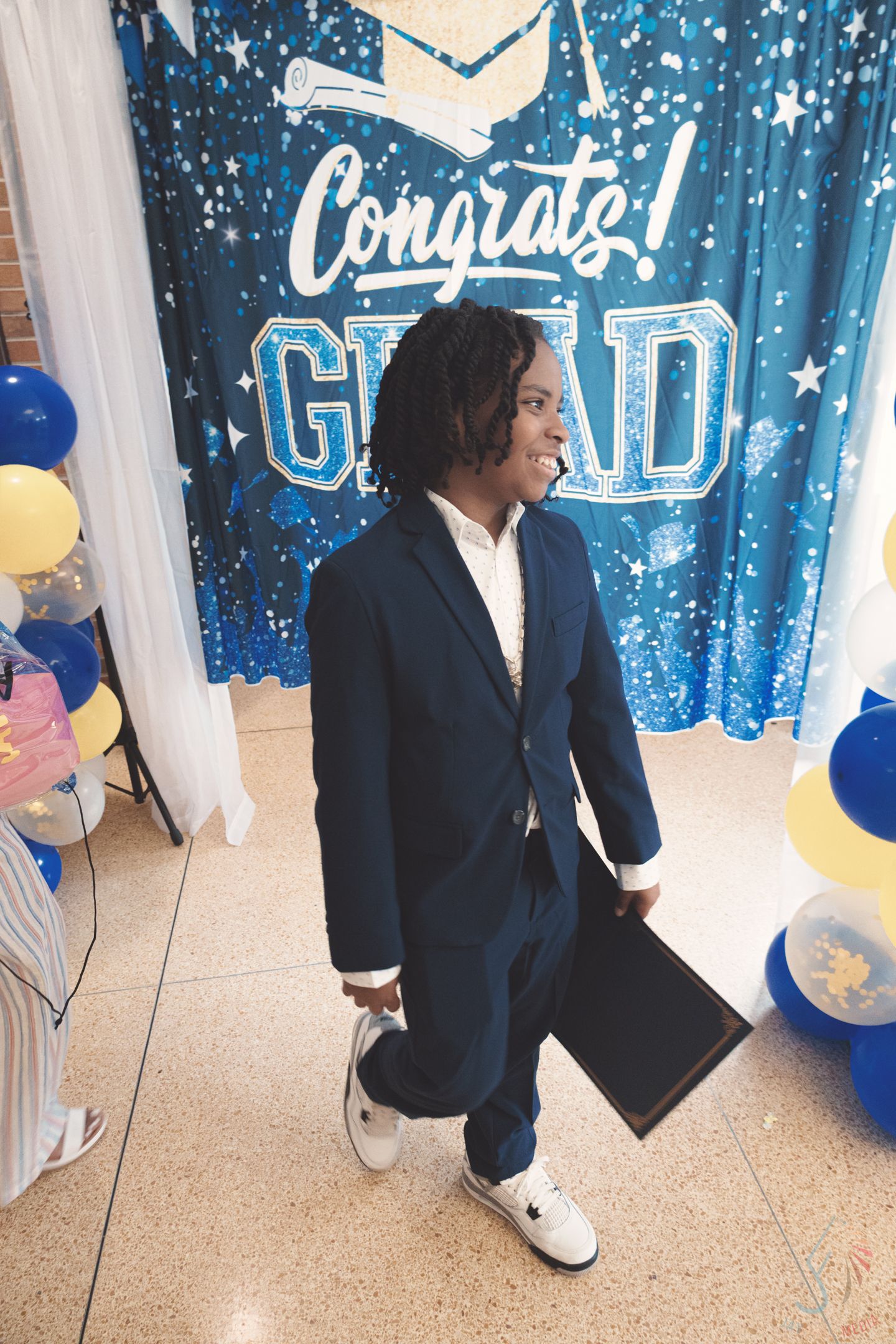 Graduation celebration setup with blue starry backdrop and white drapes.