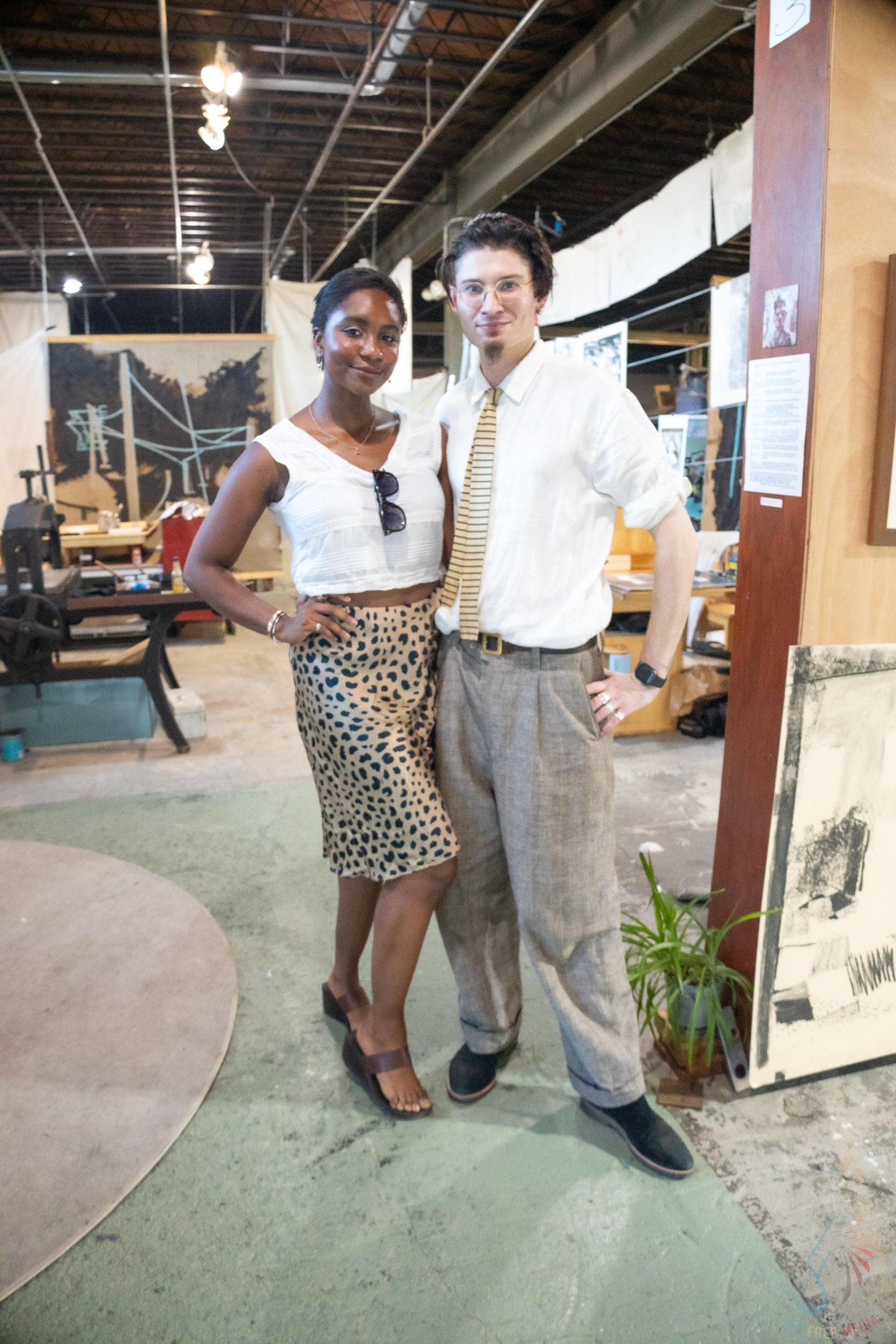 Man and woman posing together in an eclectic furniture store, wearing smart casual outfits.