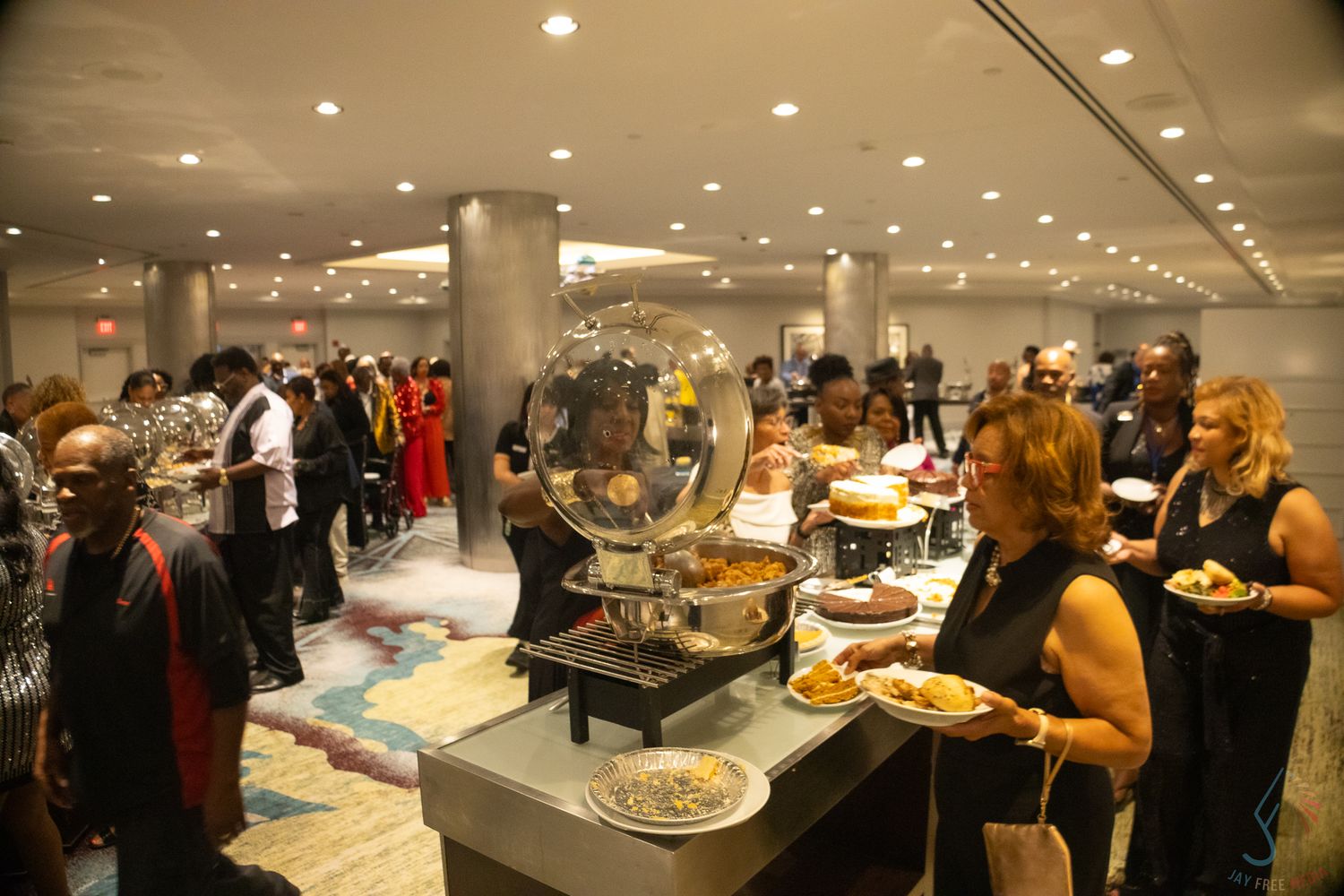 Guests fill their plates at an elegant indoor buffet during a formal evening reception event.