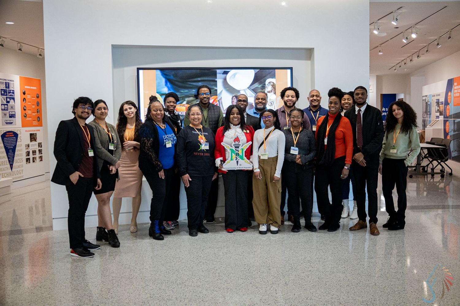 Large diverse group of professionals pose together inside a modern museum or gallery space.