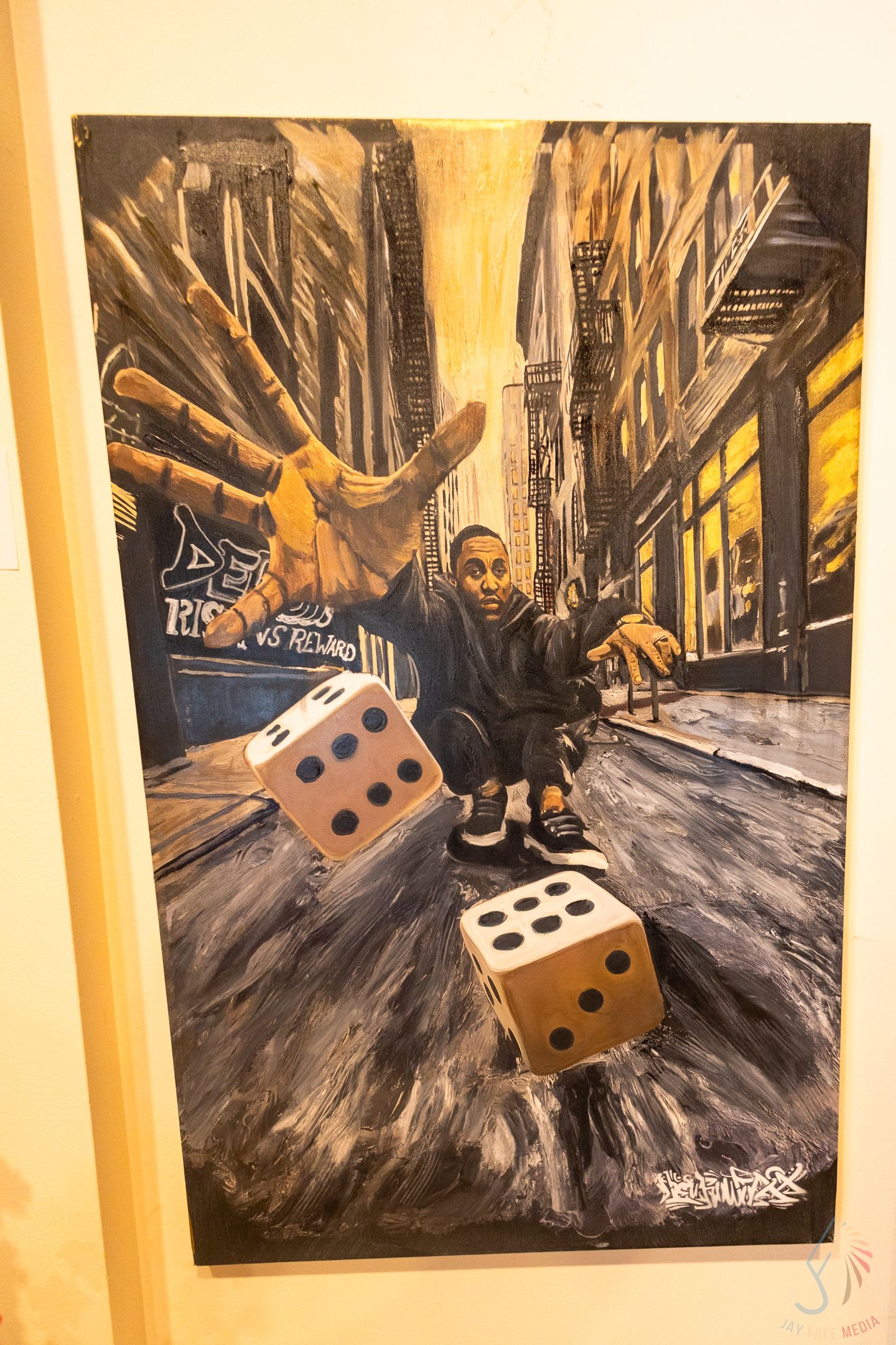 Urban street art painting featuring a man crouching with giant dice and a large hand in a city alley backdrop.
