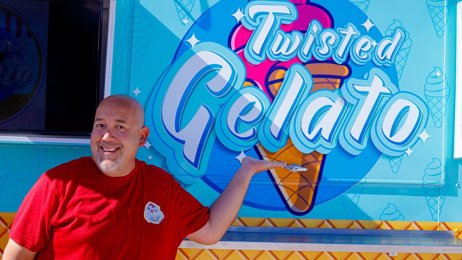 Man in red shirt pointing at Twisted Gelato food truck sign at outdoor event.