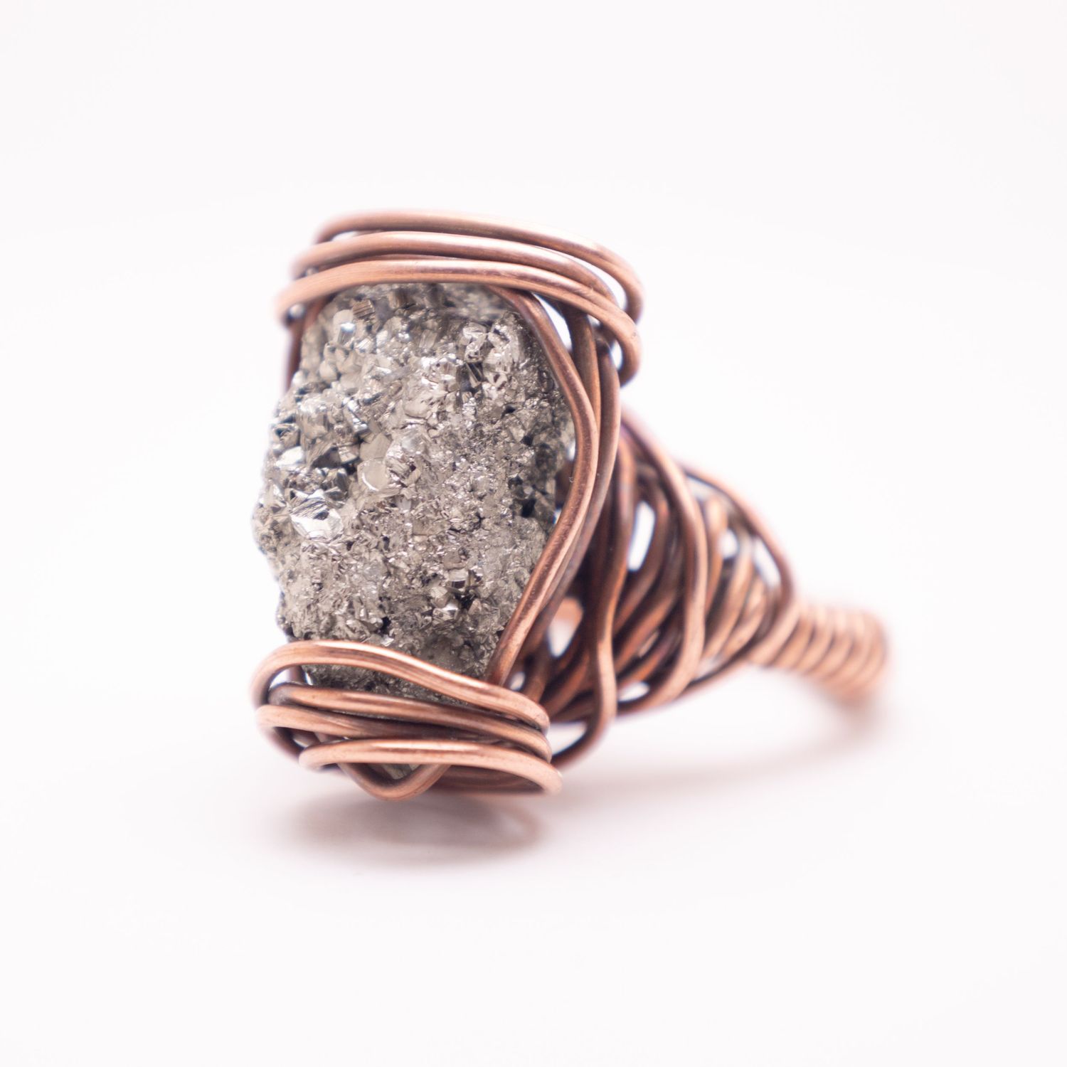 Handmade copper wire wrapped ring featuring a rough pyrite stone with metallic silver sparkle on white background.